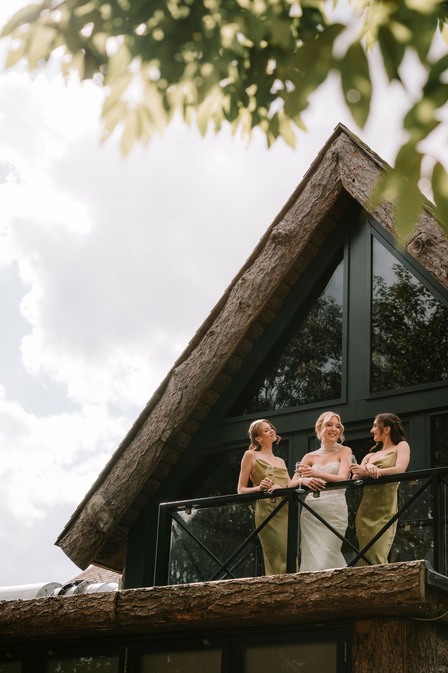 Three people enjoying a relaxing moment on a rustic balcony of a cabin with a thatched roof.