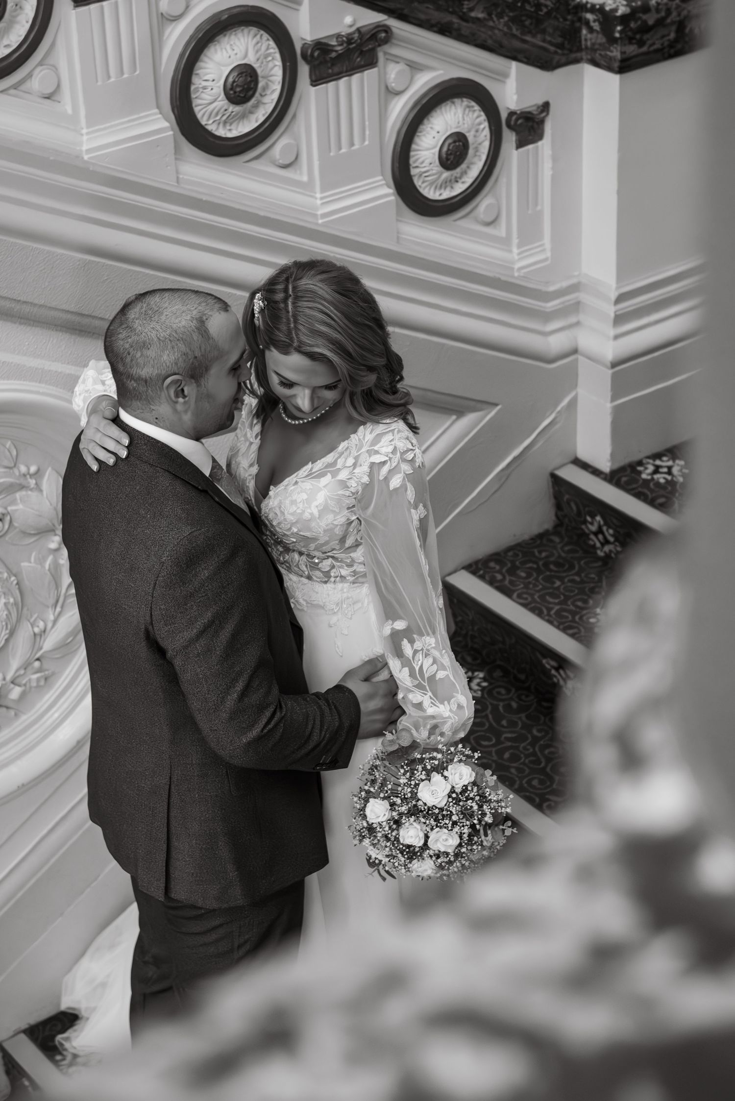 Black and white photo of a romantic dance moment on ornate staircase.