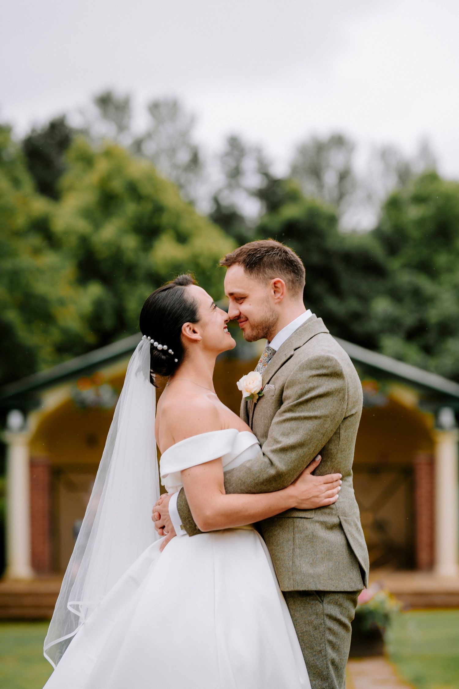 Joyful wedding portraits taken outdoors with wooden cabins in background.