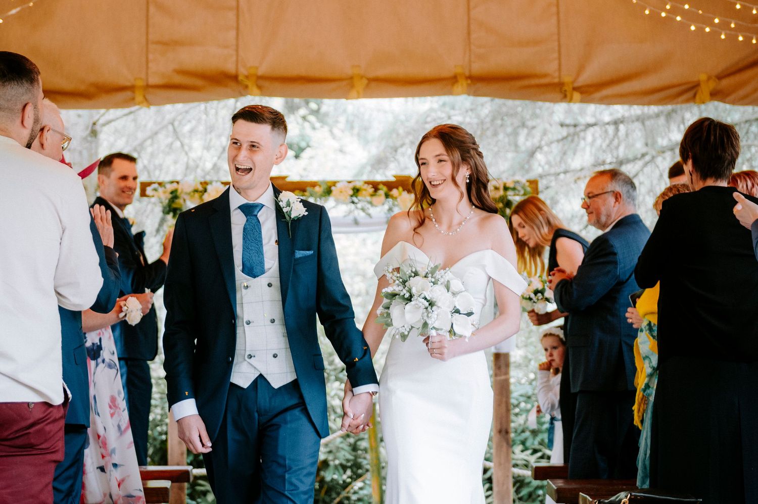 Wedding celebration in a rustic barn venue decorated with twinkling string lights overhead.