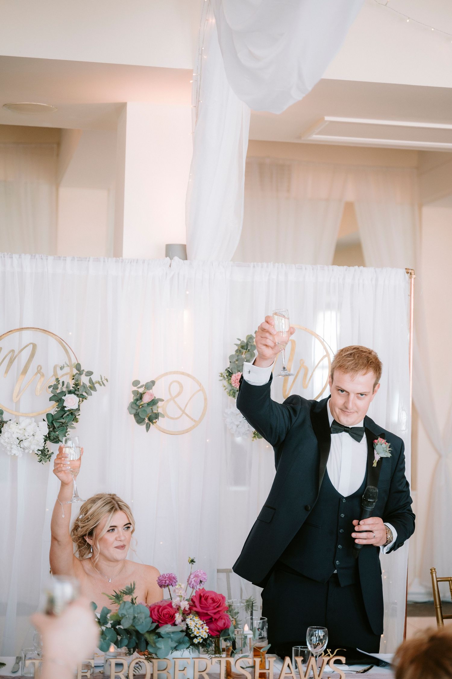 Wedding reception guests wave white napkins in celebration during a joyful dinner party moment.