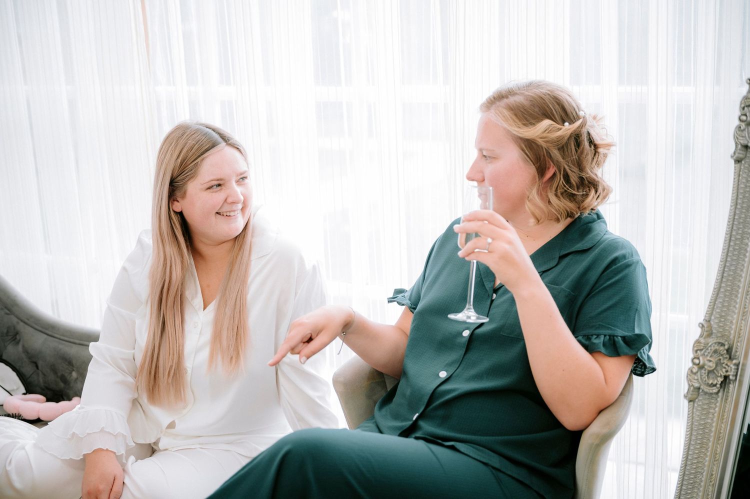 Joyful pre-wedding preparations in a bright indoor setting with white curtains.