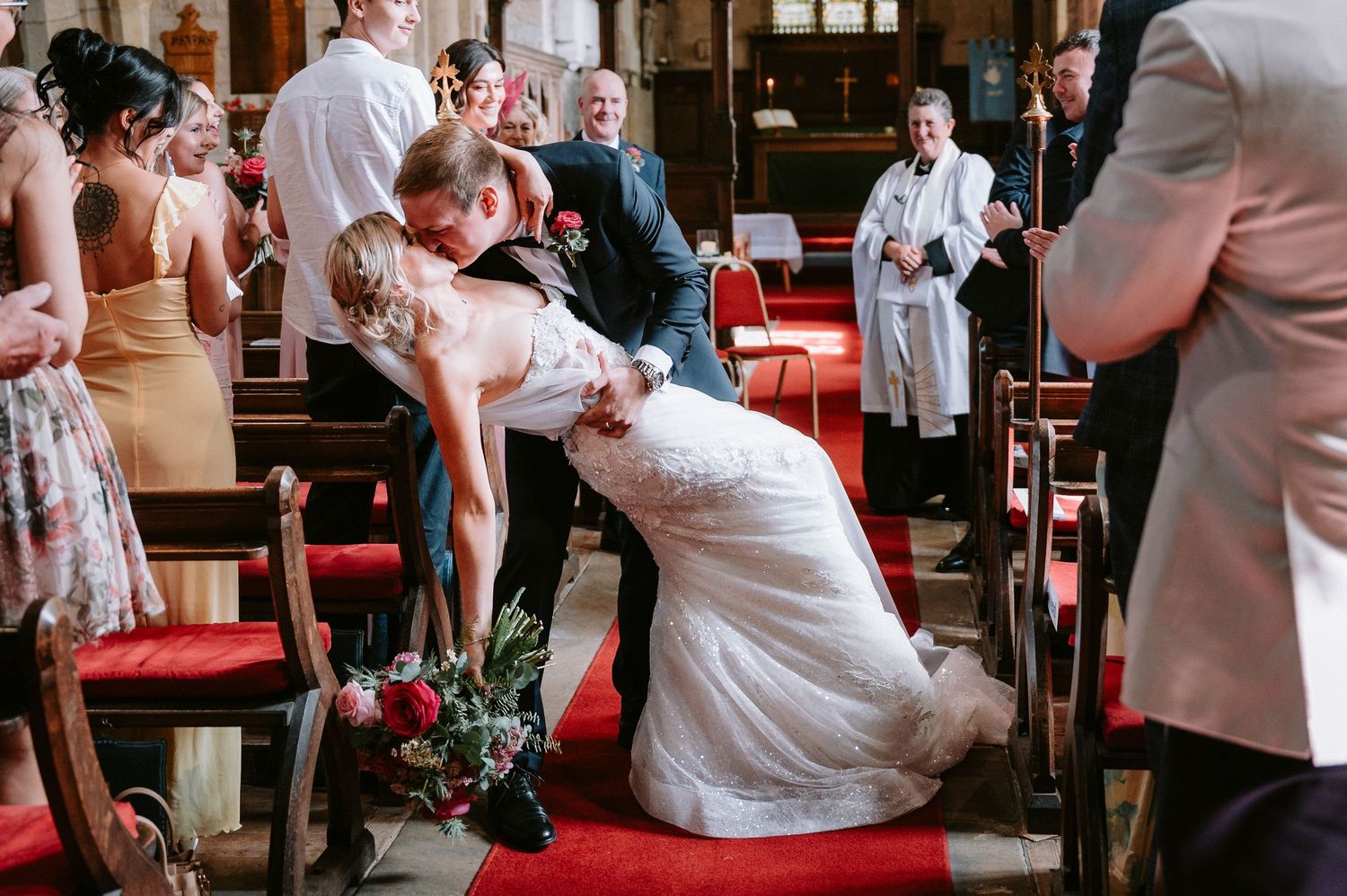 Wedding ceremony candid moments in a historic church with red chairs and stone architecture.