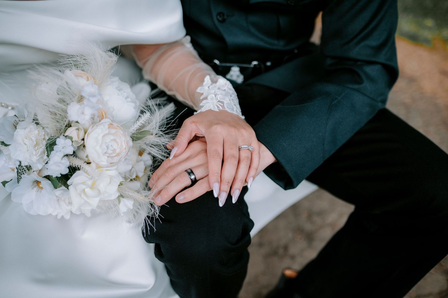 Close-up of wedding rings and white floral bouquet arrangements.