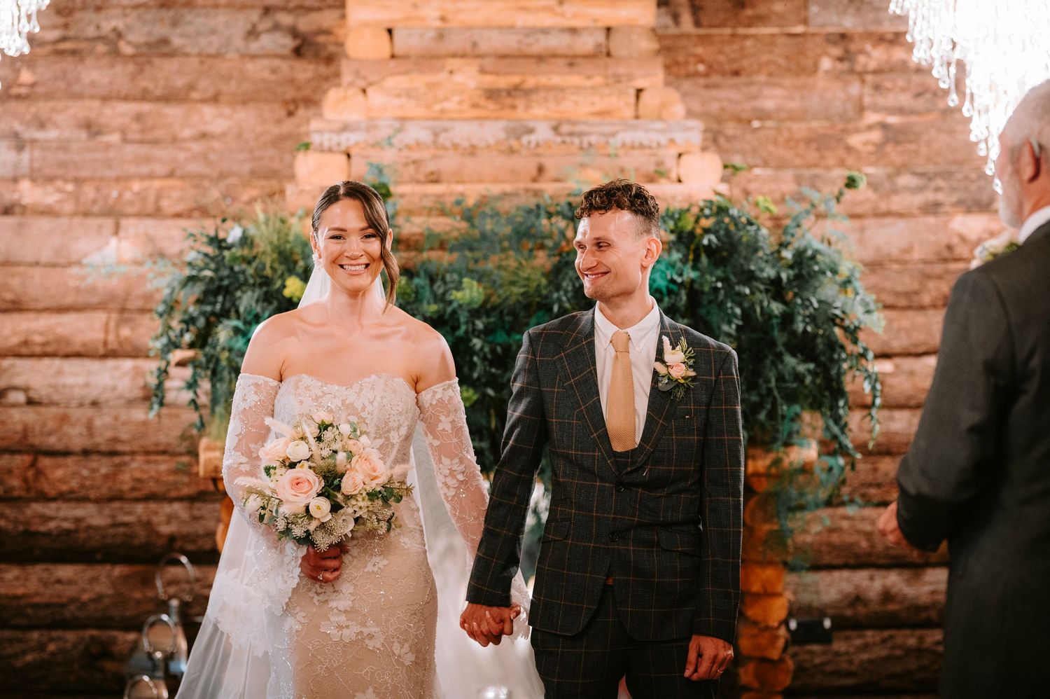 Wedding ceremony in rustic brick venue with greenery and floral decorations.