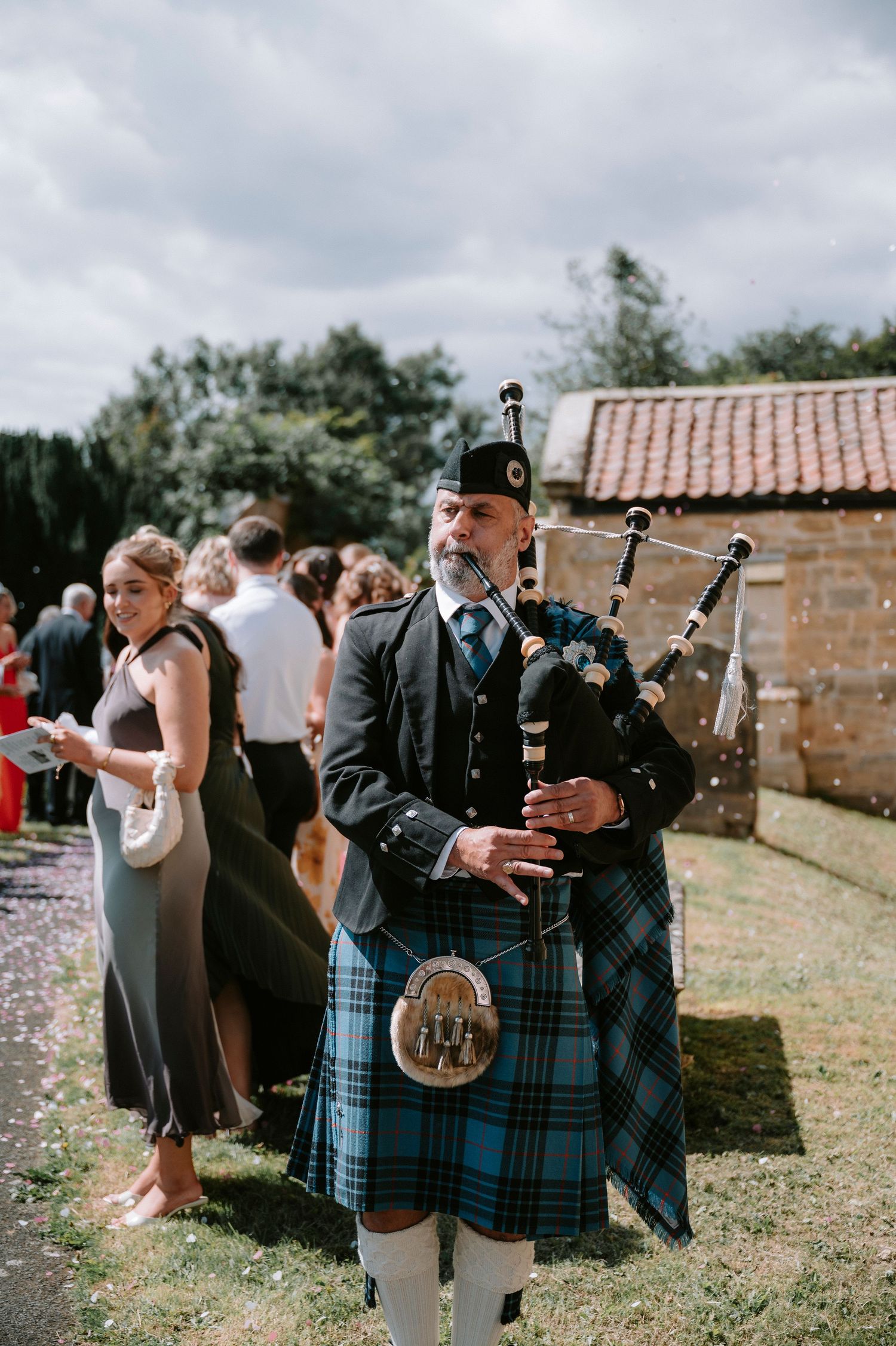 Bagpipe players in traditional Scottish kilts perform at outdoor wedding ceremony.