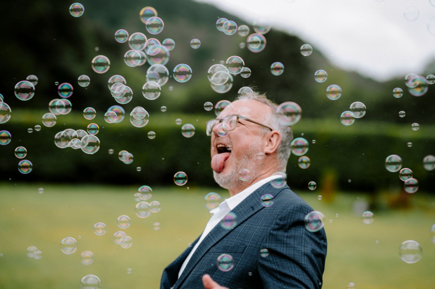 Soap bubbles float through air during outdoor wedding celebration.