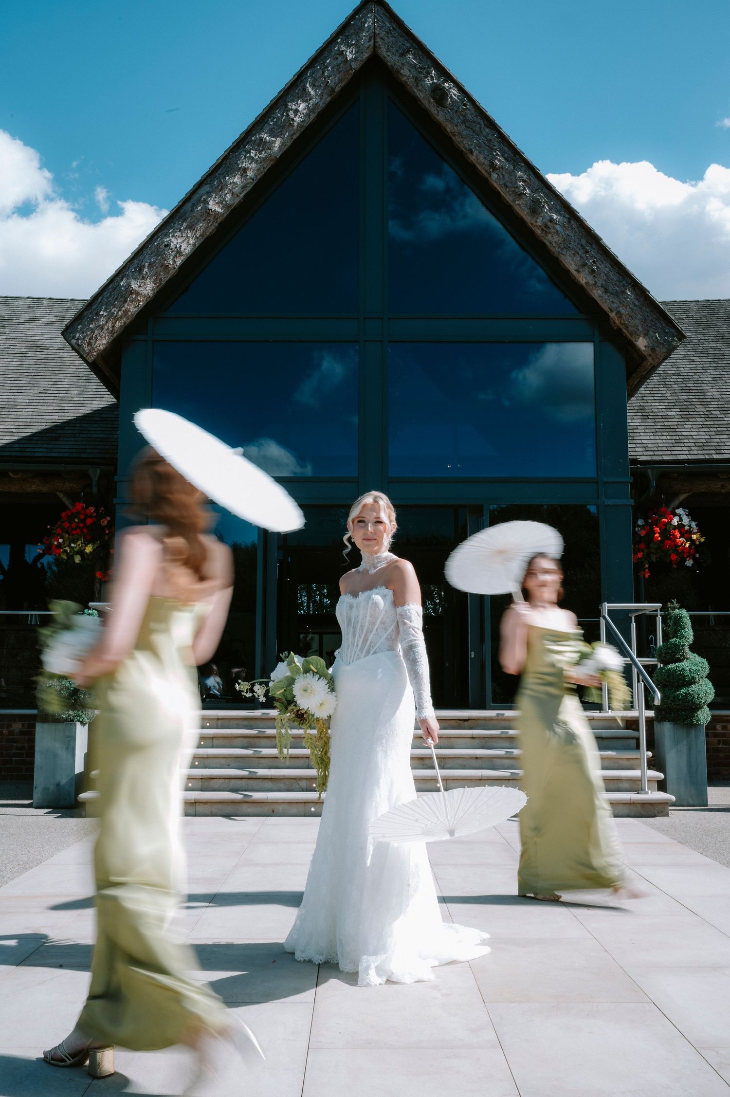 Motion blur captures bridesmaids in yellow dresses circling around a bride in white on an outdoor patio.
