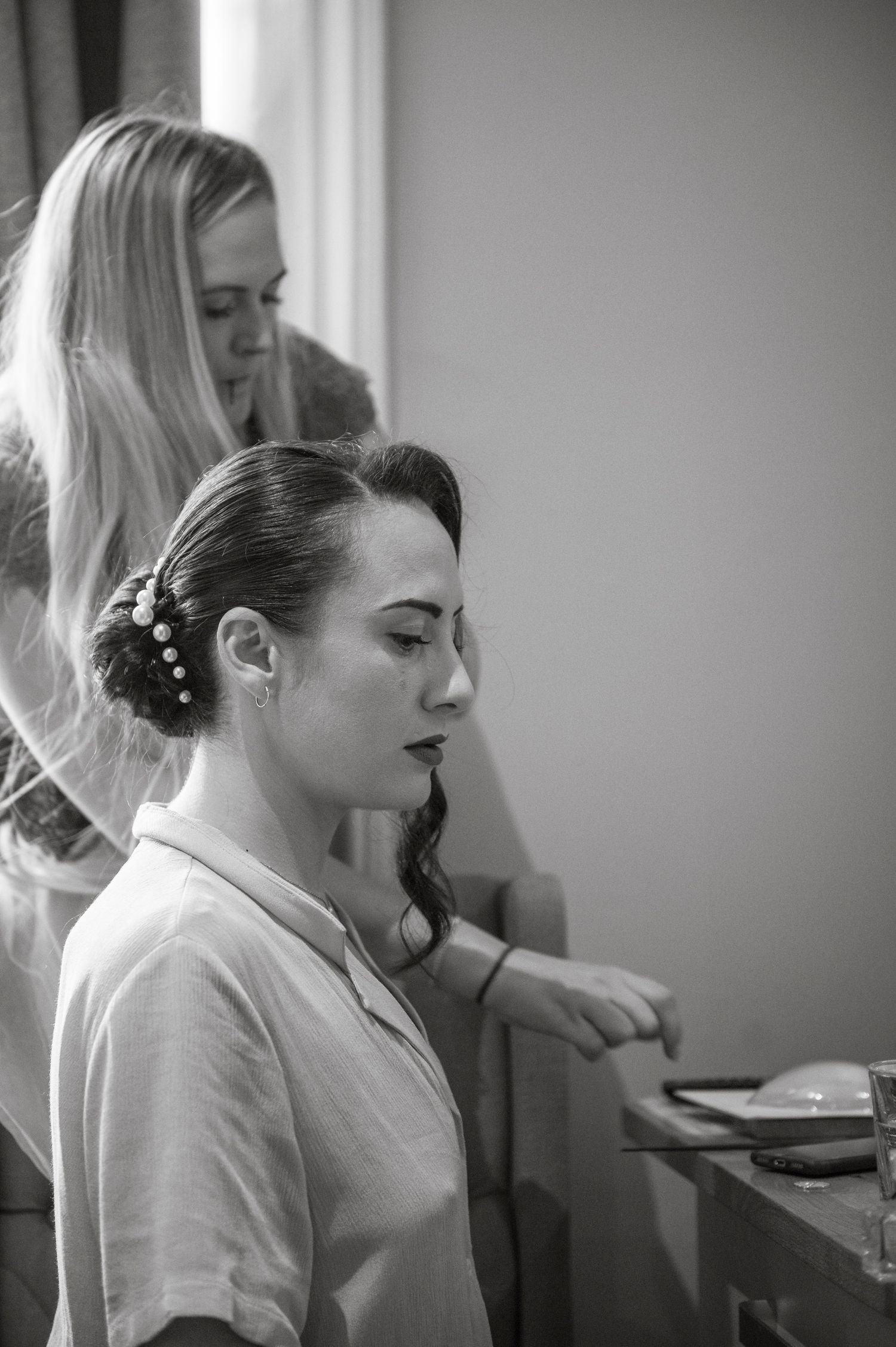 Wedding preparation scene with elegant hairstyles and natural lighting.