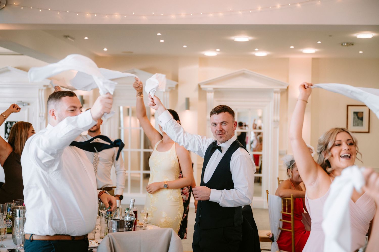 Wedding guests participate in a napkin waving tradition during the reception celebration.