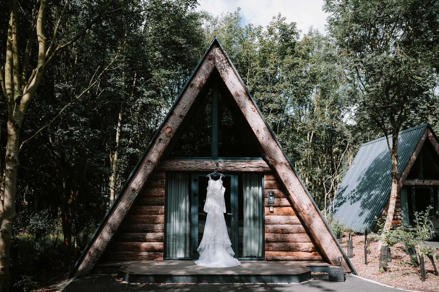 A-frame wooden cabins nestled among trees create a rustic wedding venue setting.
