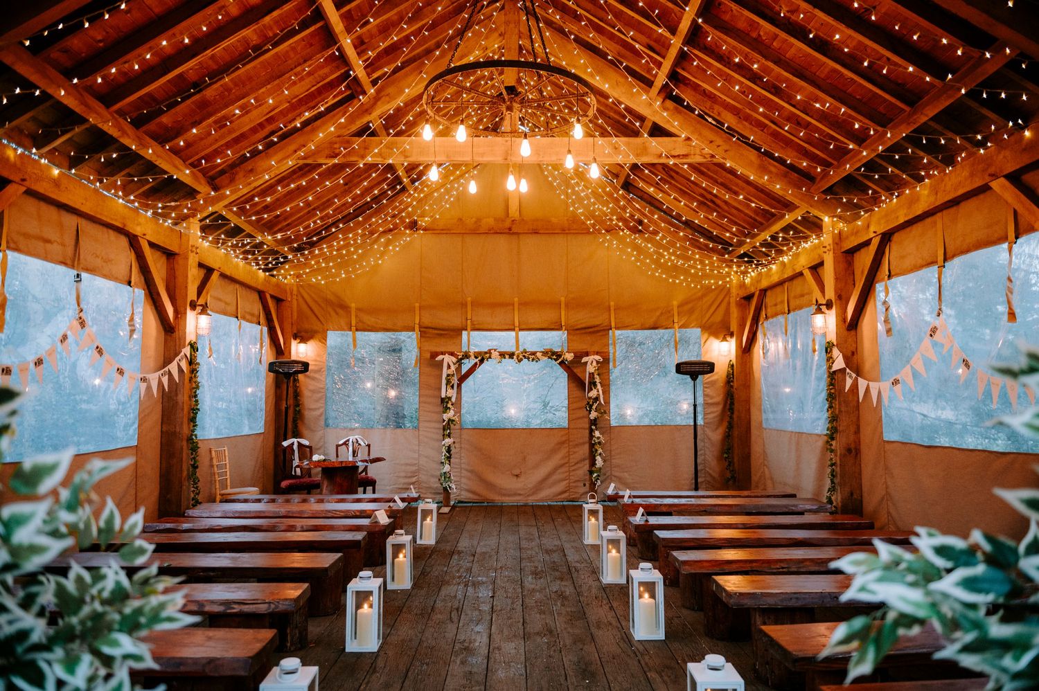 A rustic barn wedding venue with wooden beams and romantic string light decorations.