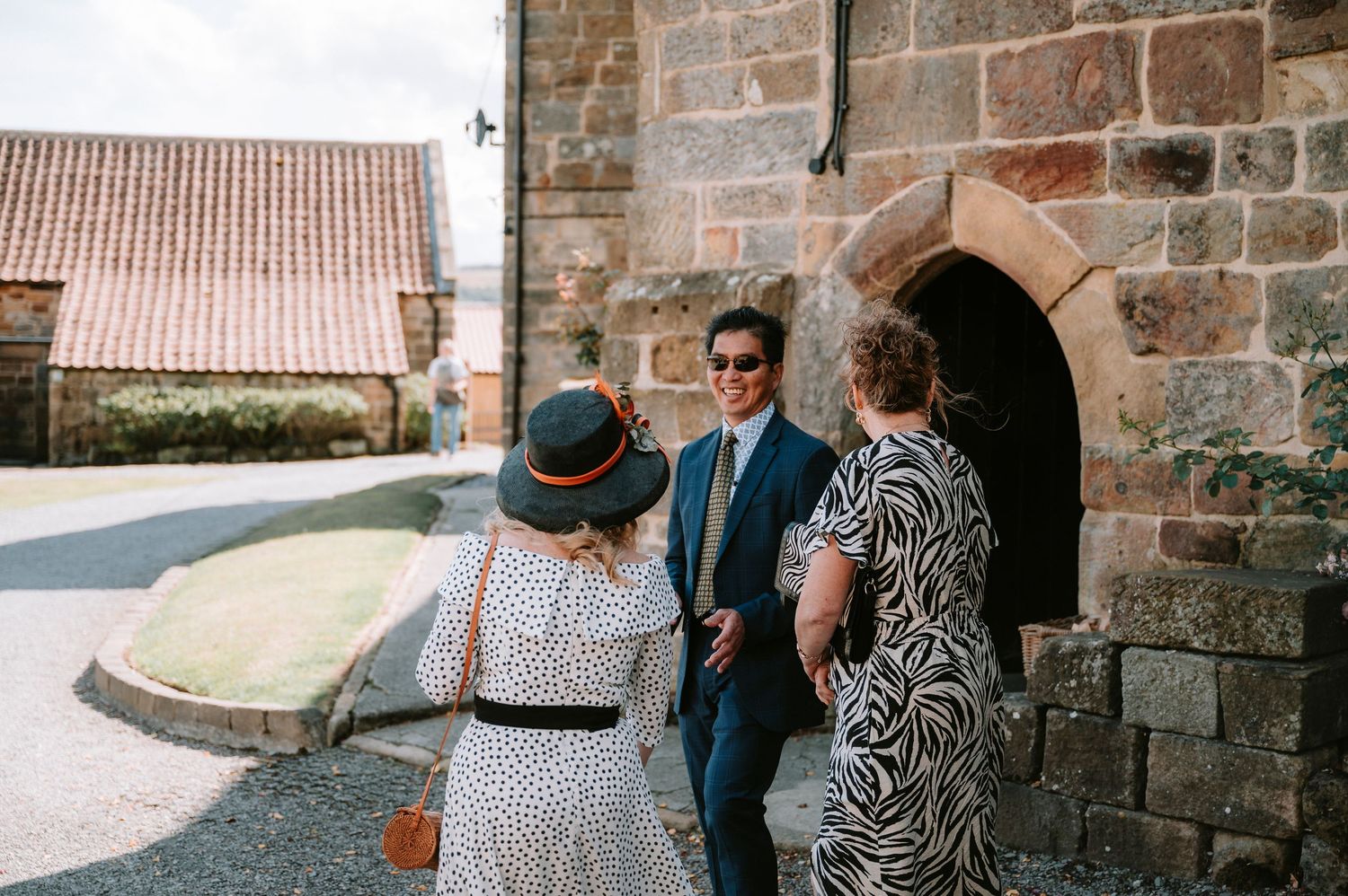 Wedding guests gathered outside historic stone building during outdoor ceremony.