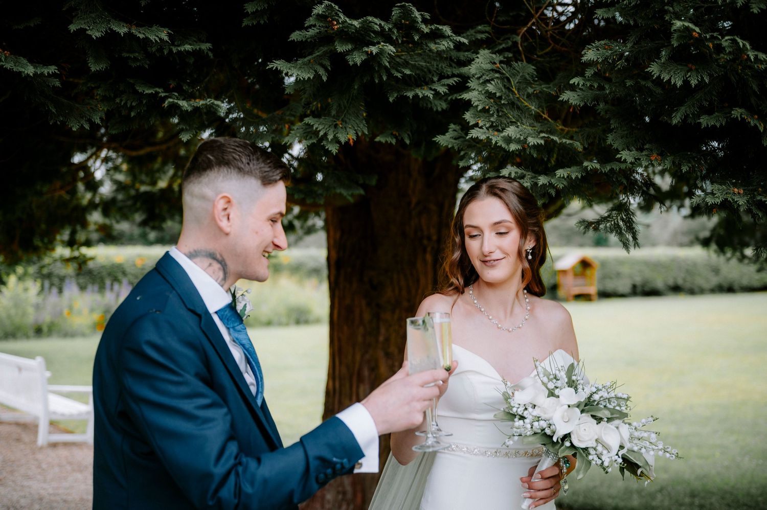 Elegant outdoor wedding photography session in a garden setting with white floral bouquet.