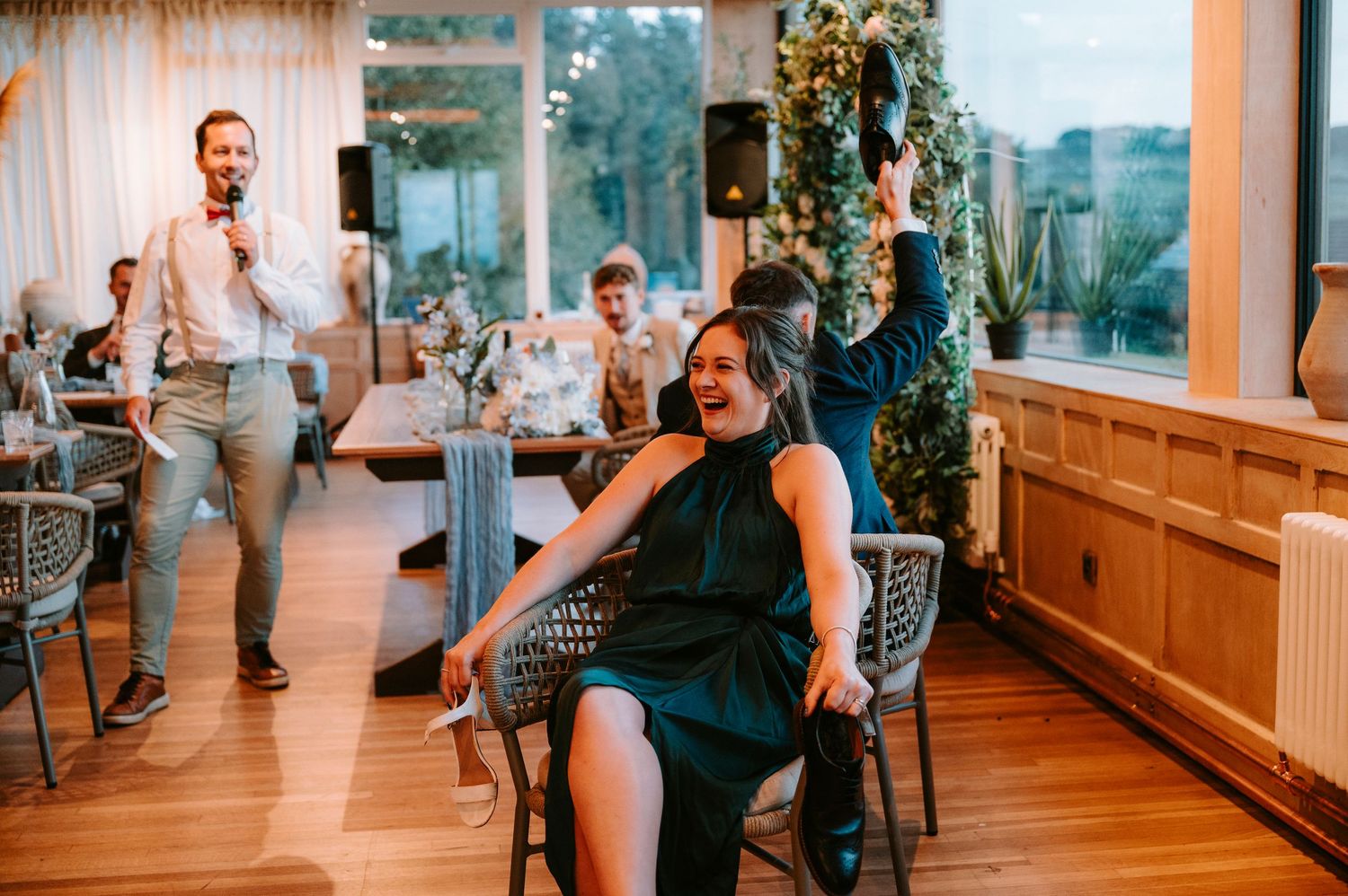 Wedding reception guests enjoying lively celebration in indoor venue with wood floors.