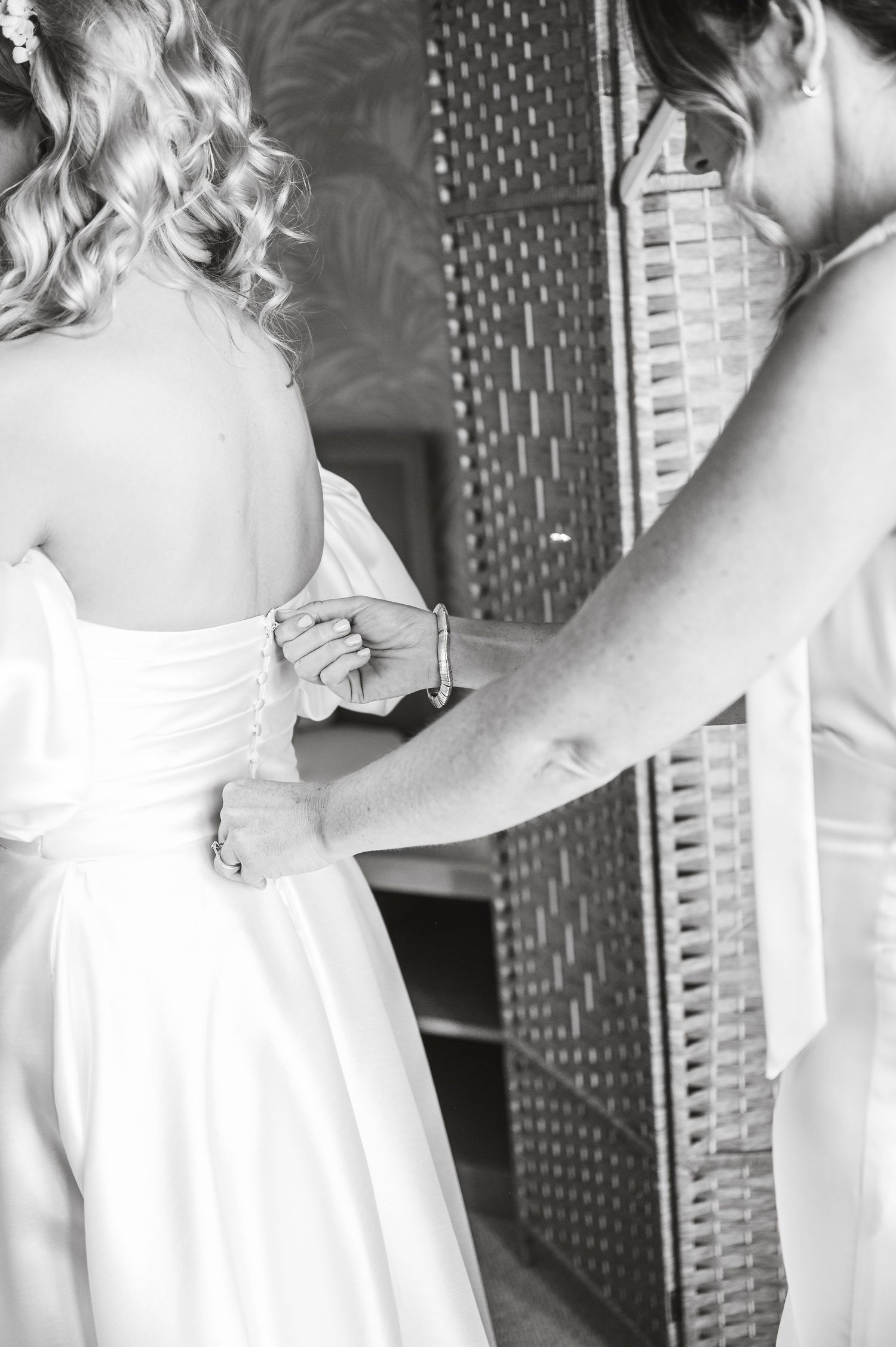 Black and white photo showing final wedding dress adjustments being made before ceremony.