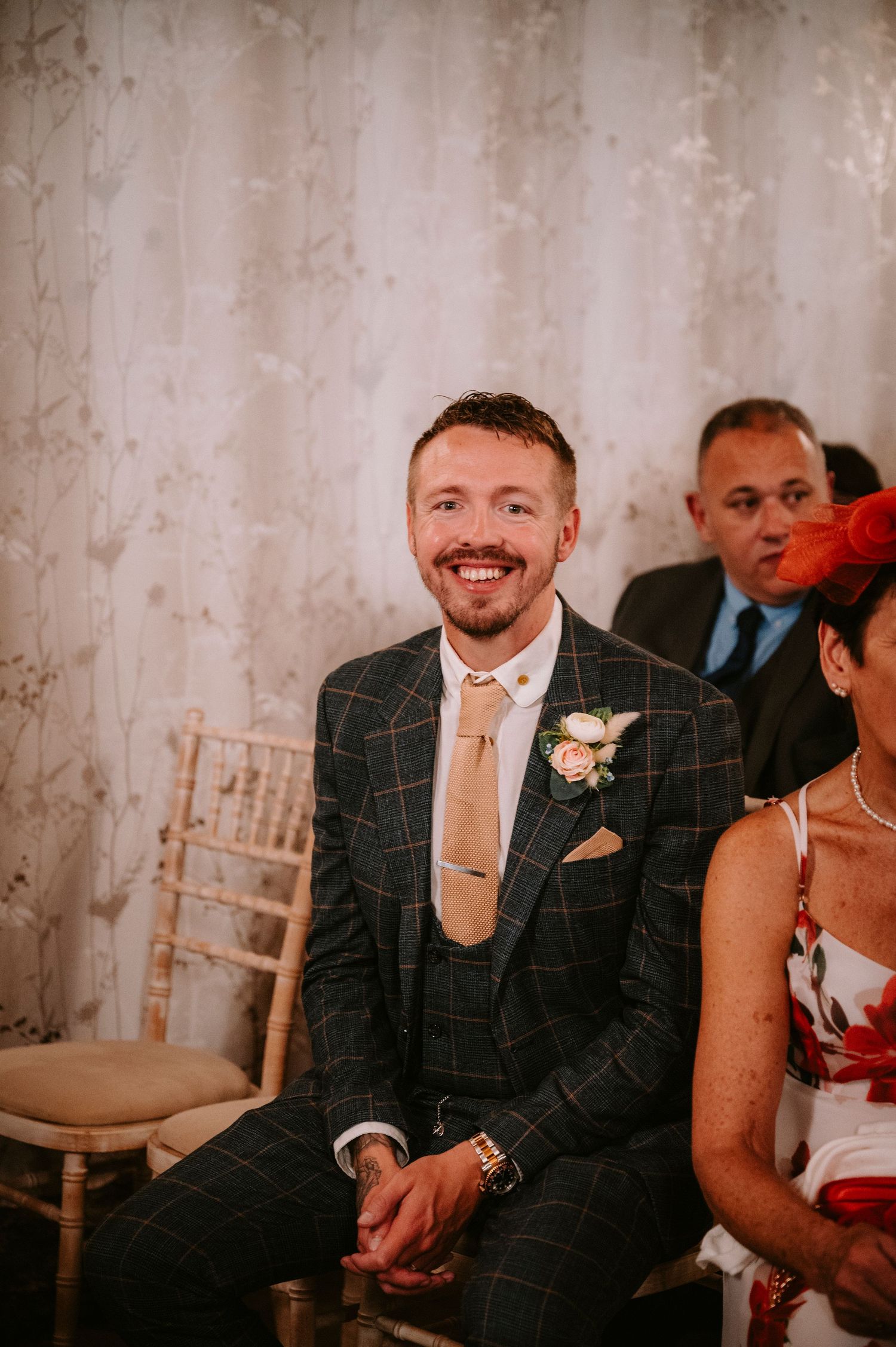 Wedding guests seated in formal attire at an elegant indoor reception.