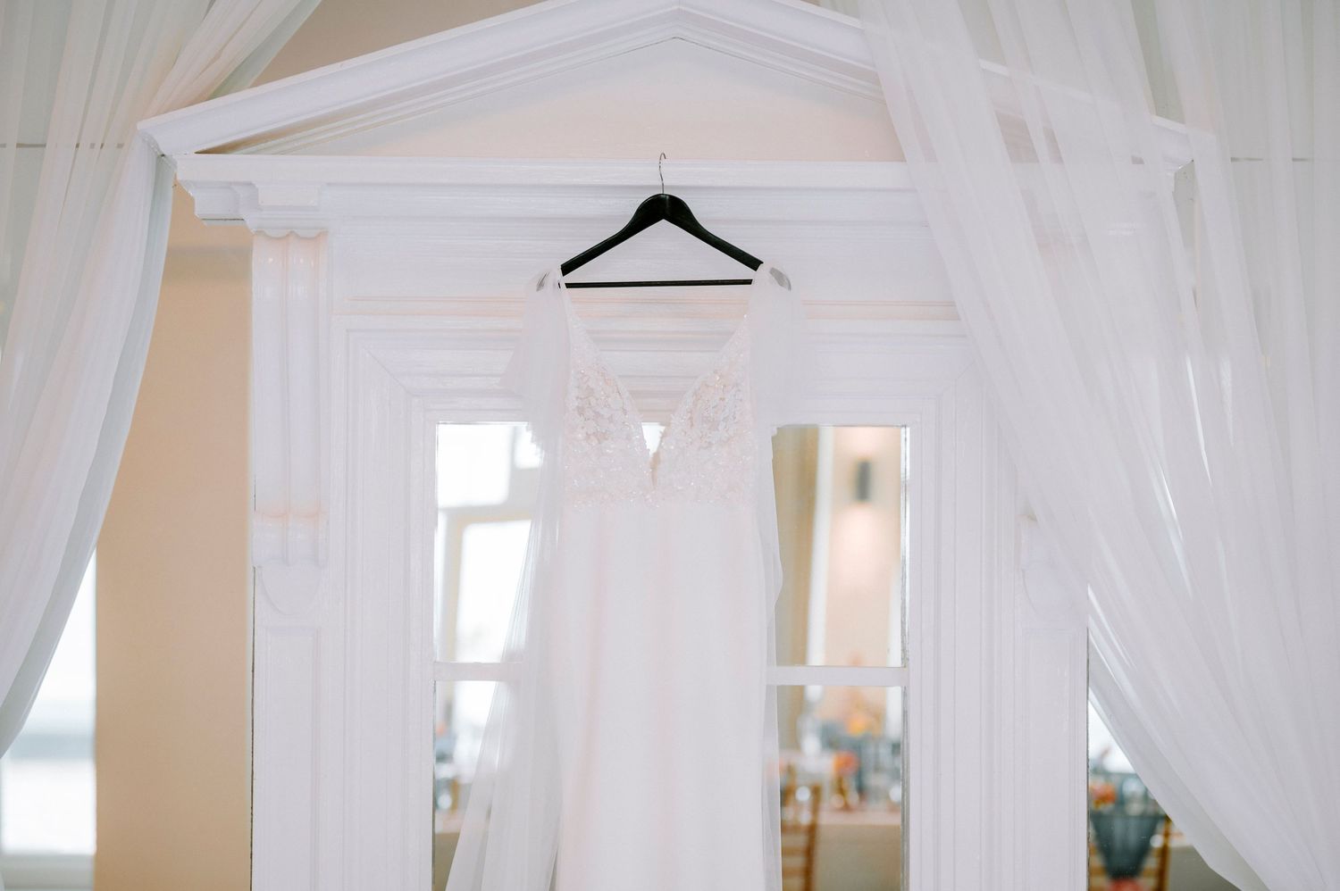 Bright white dressing room with sheer curtains and natural window lighting.