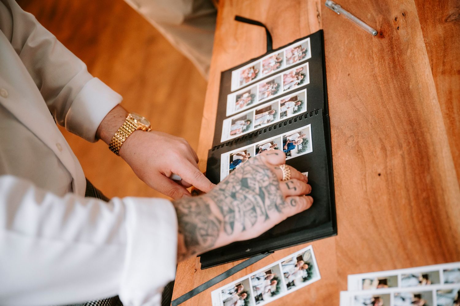 Hands in white sleeves flipping through a photo album with vintage photographs arranged on black pages.