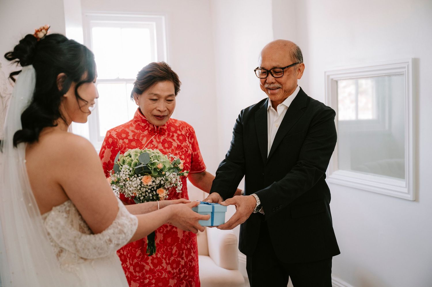 Wedding ceremony preparations in a bright white room with traditional attire and tea ceremony elements.