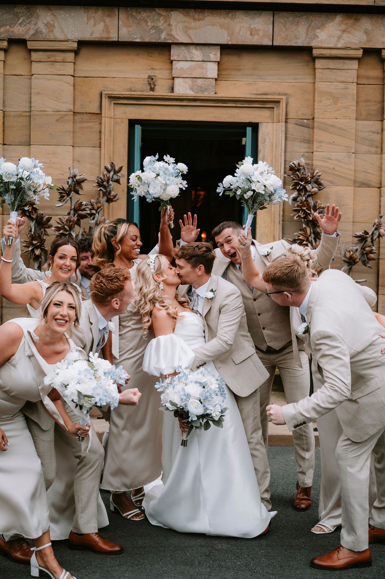 Fun wedding party photo sequence showing group jumping and celebrating against stone building backdrop.