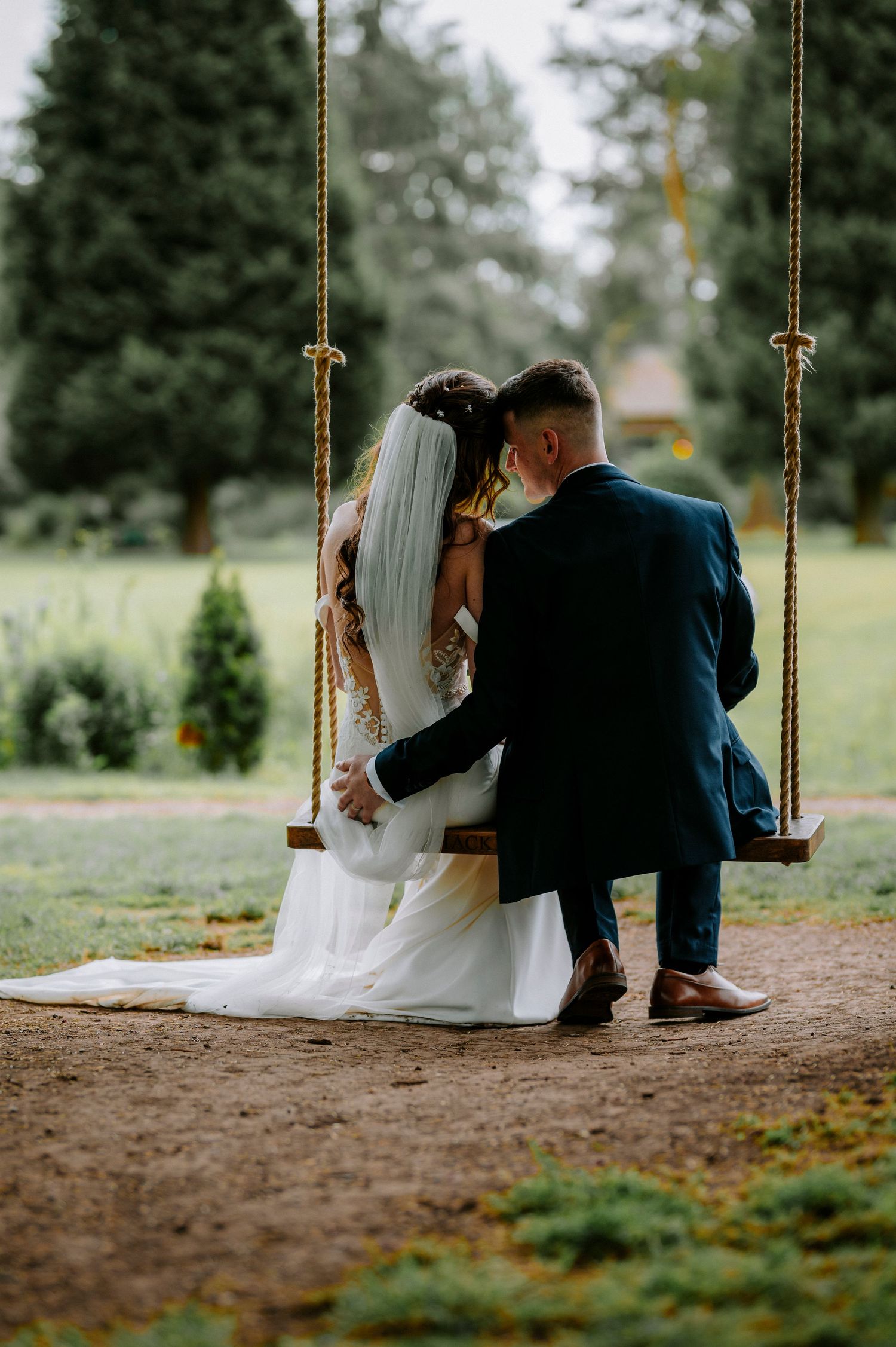 Wedding couple sharing quiet moments together on a rustic rope swing surrounded by trees.