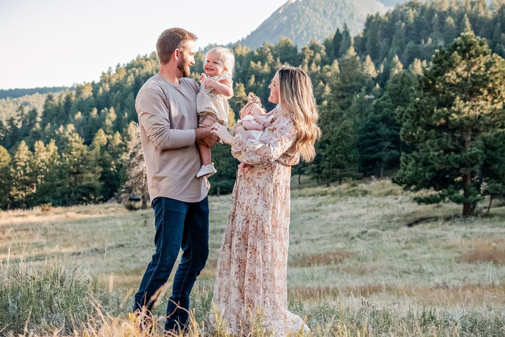A young family smiles at Halfway House on Flagstaff Mountain, looking down at the Boulder Valley during an autumn mini session. family photo
