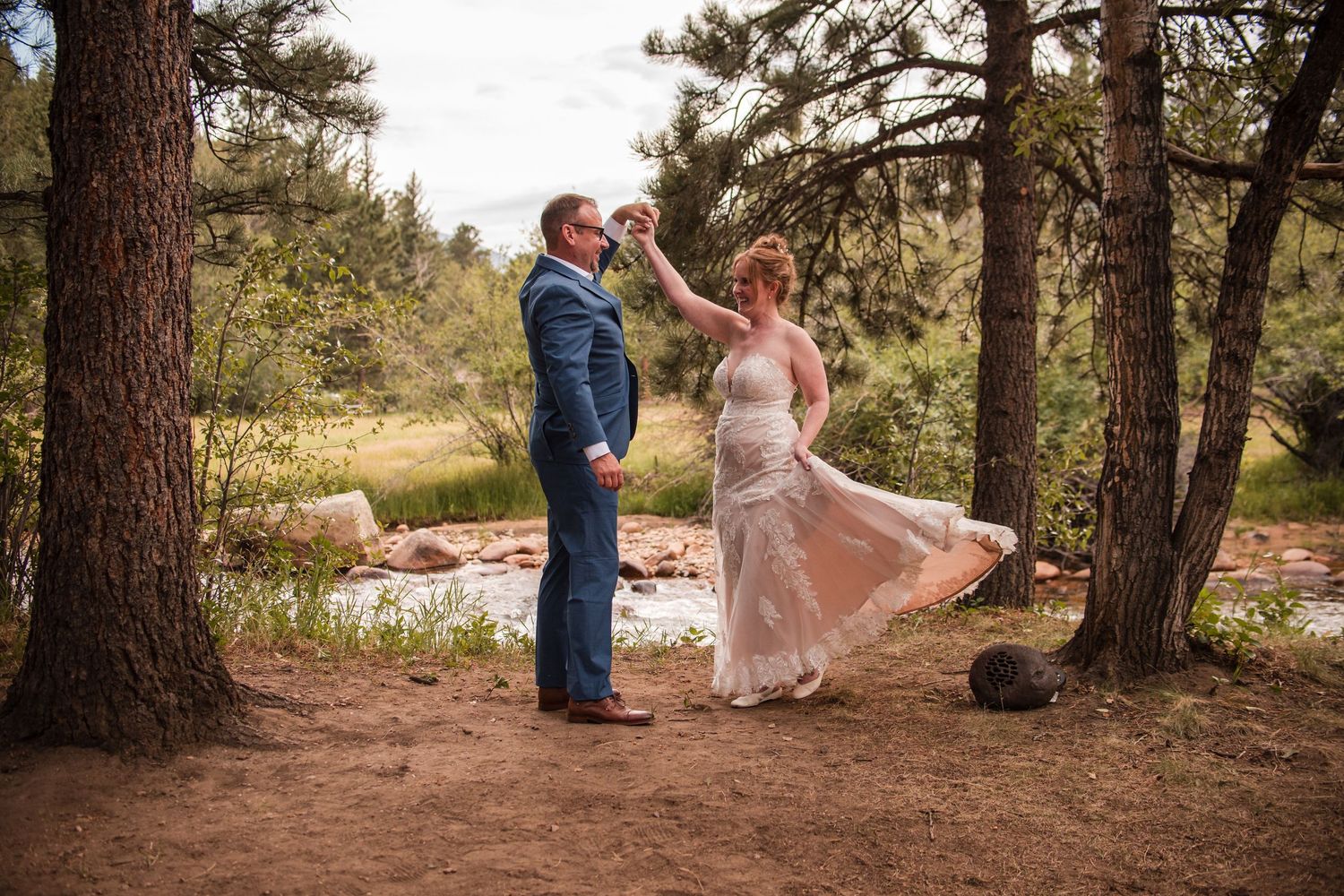 Bride and groom dancing among pine trees in a forest clearing during an outdoor wedding ceremony. wedding photography angelice caballer