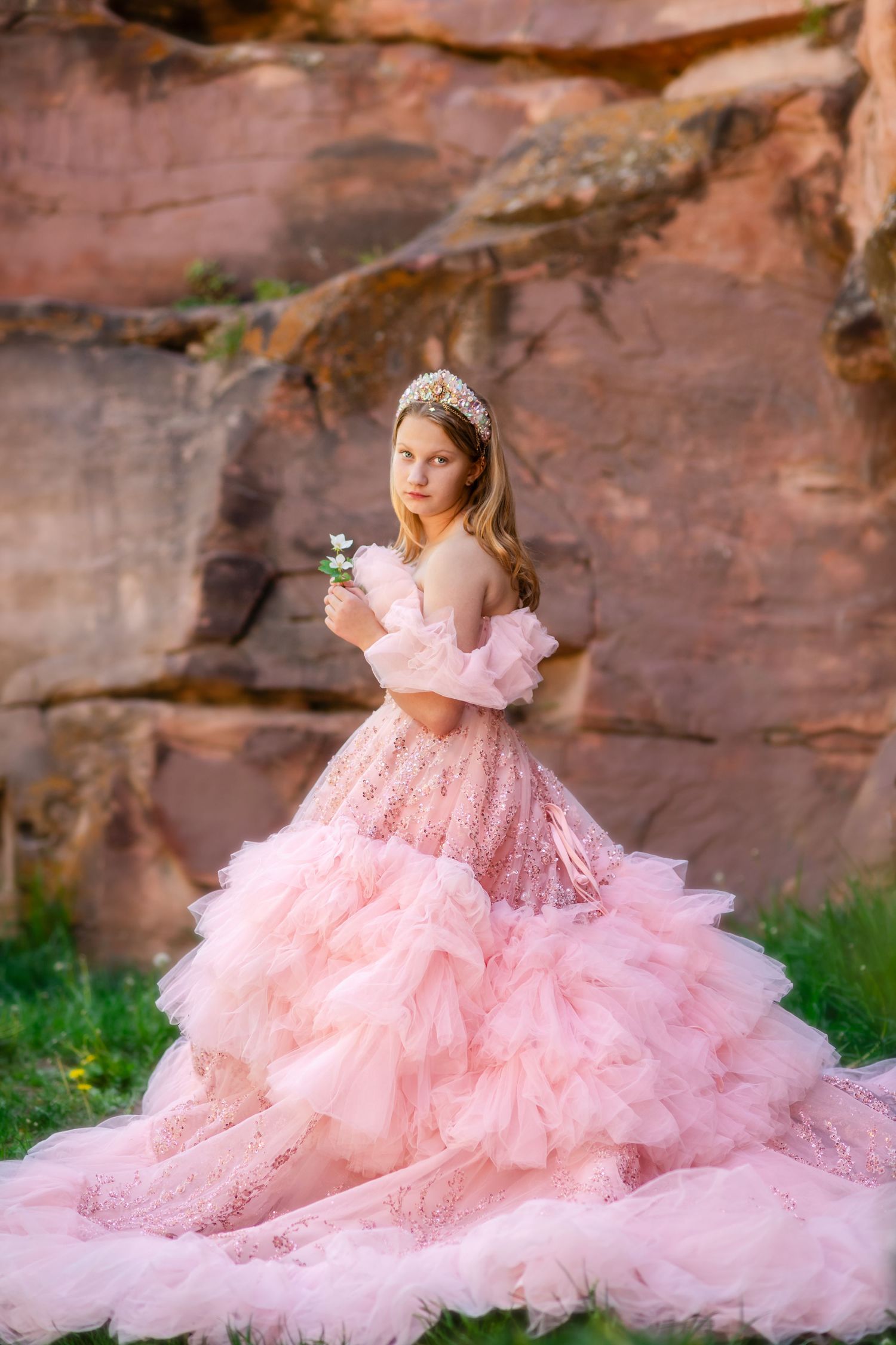 A young girl in a pink princess gown with a tiara holds a white flower. Longmont Child Photographer Little Dreamers Couture