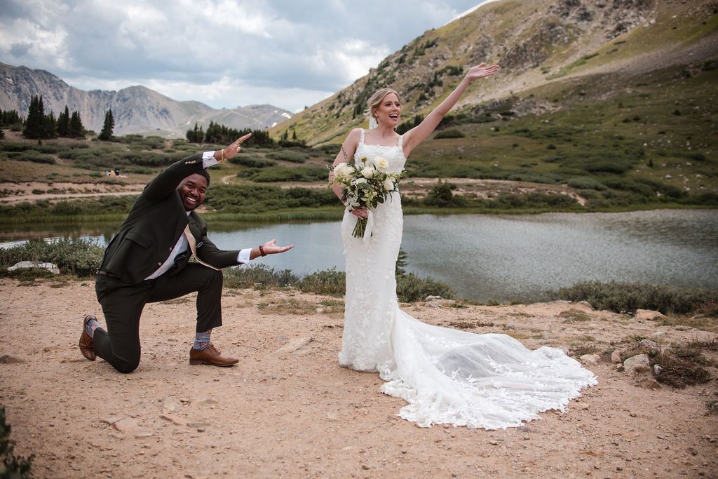 Bride and groom celebrating wedding in scenic mountain landscape with alpine lake and green hills in background. Mountain weddings