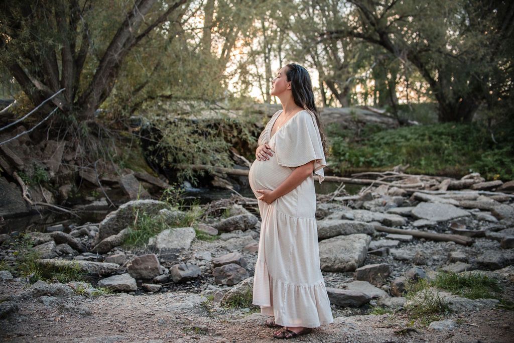 Close-up detail portrait of an expectant mother gently cradling her belly during a fall golden hour portrait session in Boulder County.