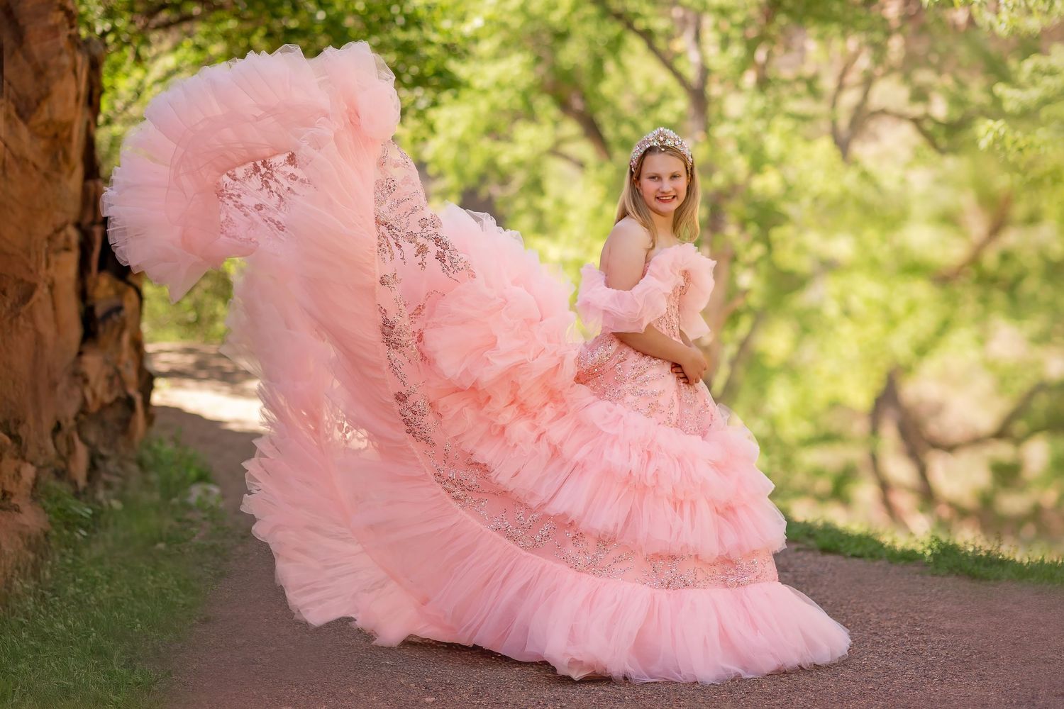 Girl pink princess gown with a ruffled train poses outdoors near trees, wearing a tiara. Fine art photography, Longmont, Little Dreamer tutu