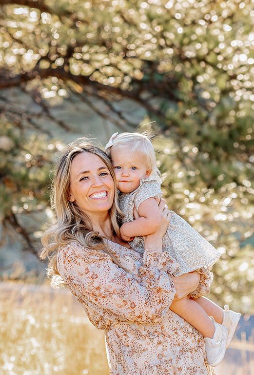 Mother holding baby in front of the historic stone structure at the Halfway House venue in Boulder, Colorado during a fall mini session