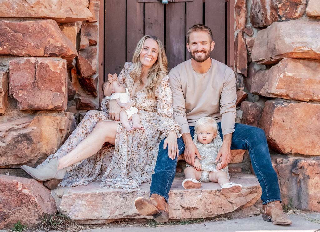 Parents holding their children in front of the historic stone structure at the Halfway House venue in Boulder, Colorado during a fall mini