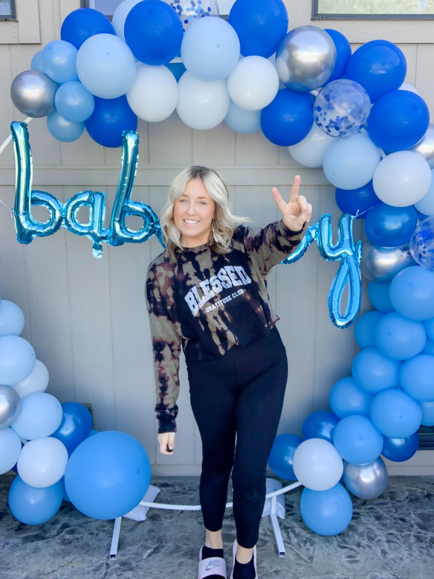 female standing in front of baby boy balloon garland photo booth setup and design