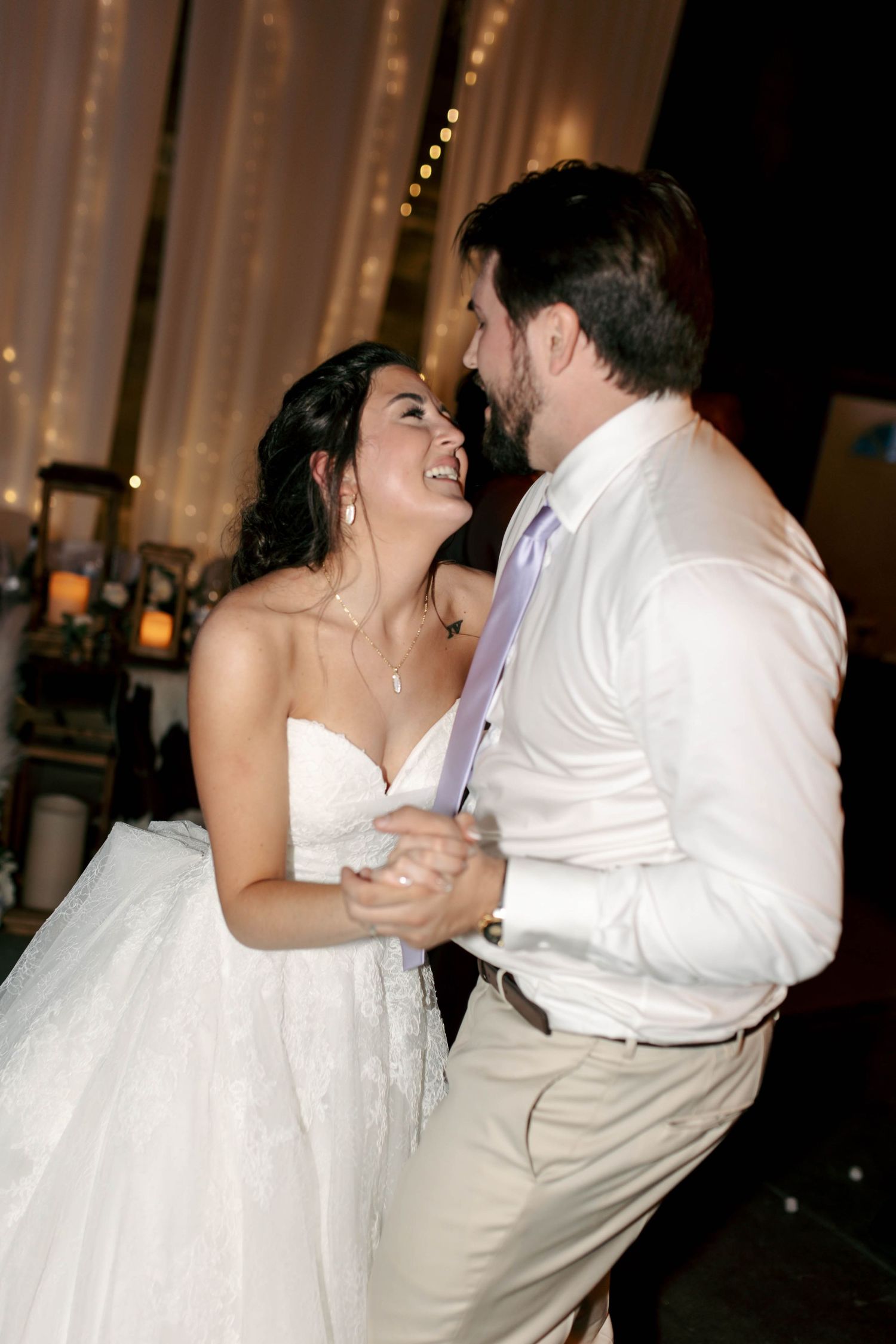 Bride and groom share their first dance, laughing joyfully together at their wedding reception.