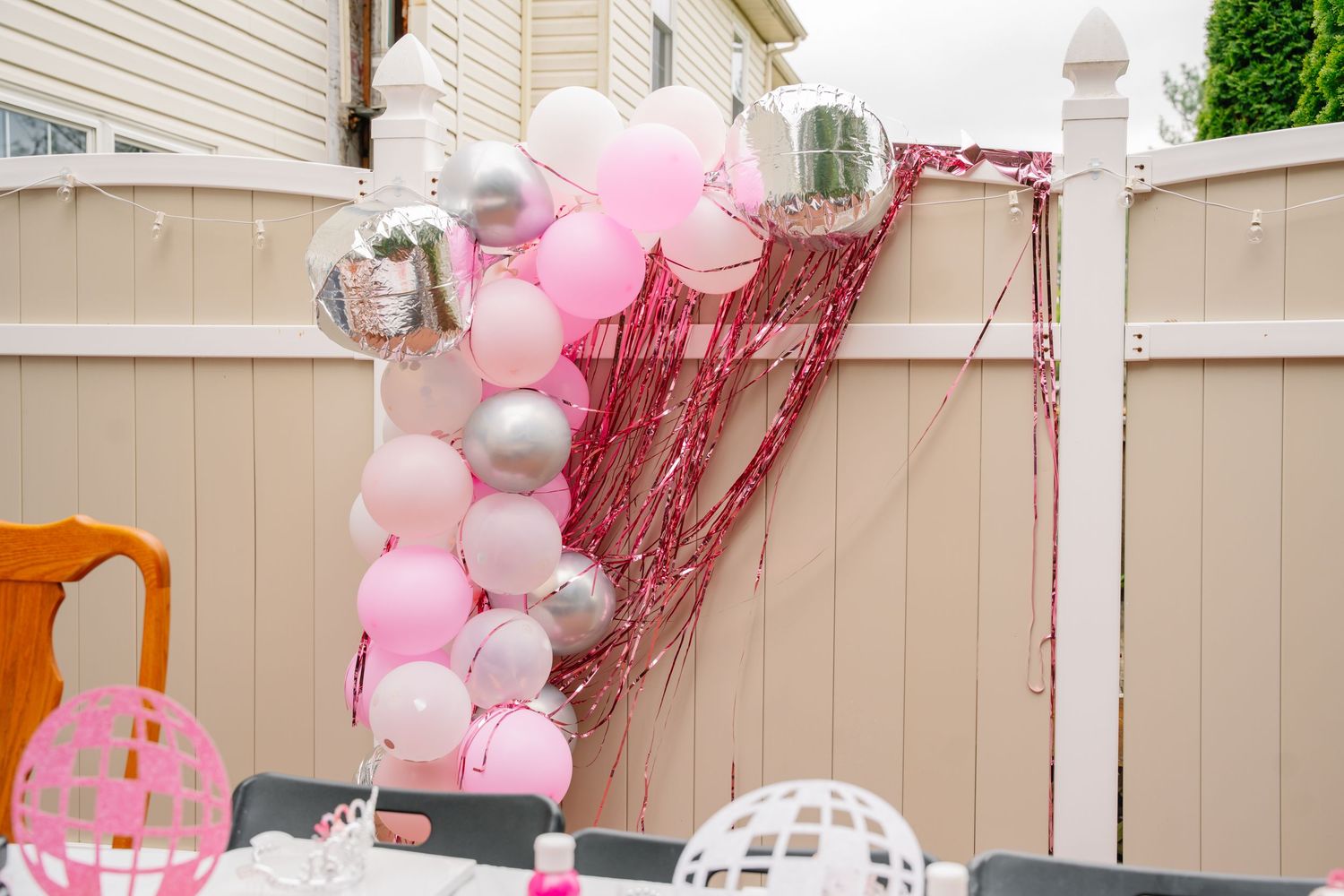 Pink, silver, and white balloon arch with red fringe backdrop at an outdoor party celebration. In Bel Air Maryland