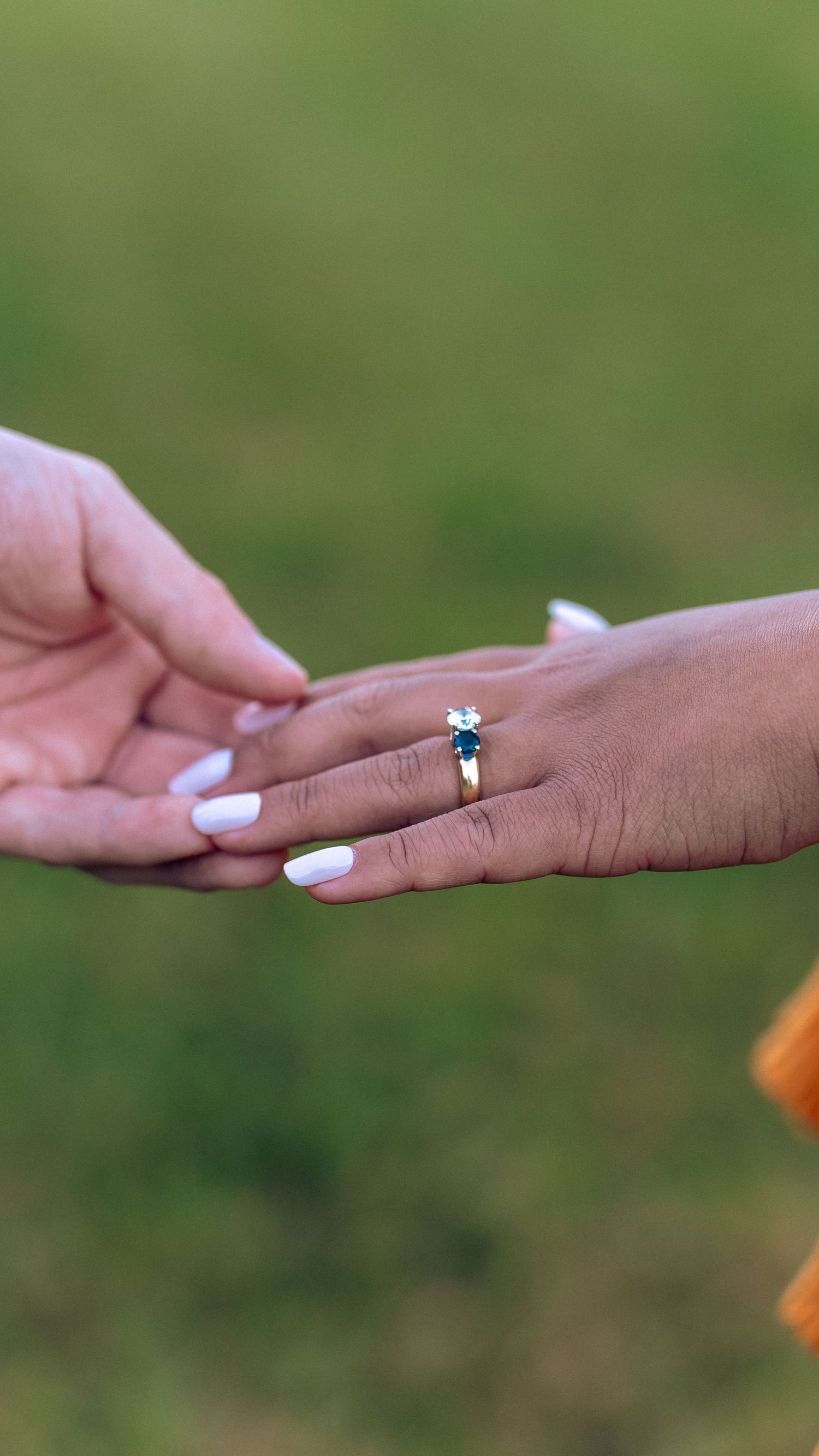 Close-up of hands touching, woman wearing gold ring with blue and white stones, white manicure. In Fallston Maryland