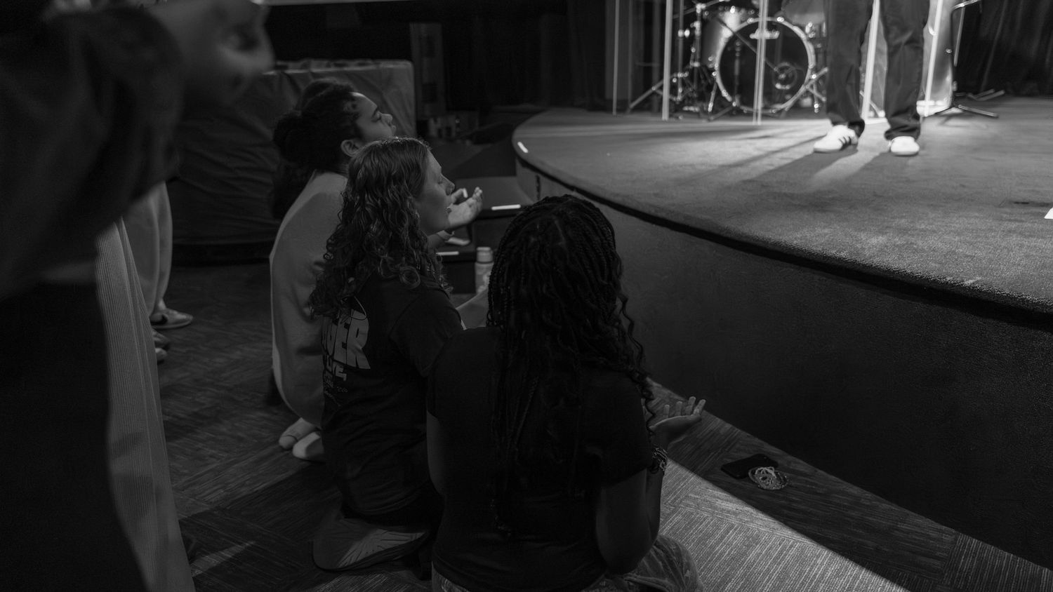 Black and white photo of people sitting on floor near a stage during a live music event. In Abingdon Maryland