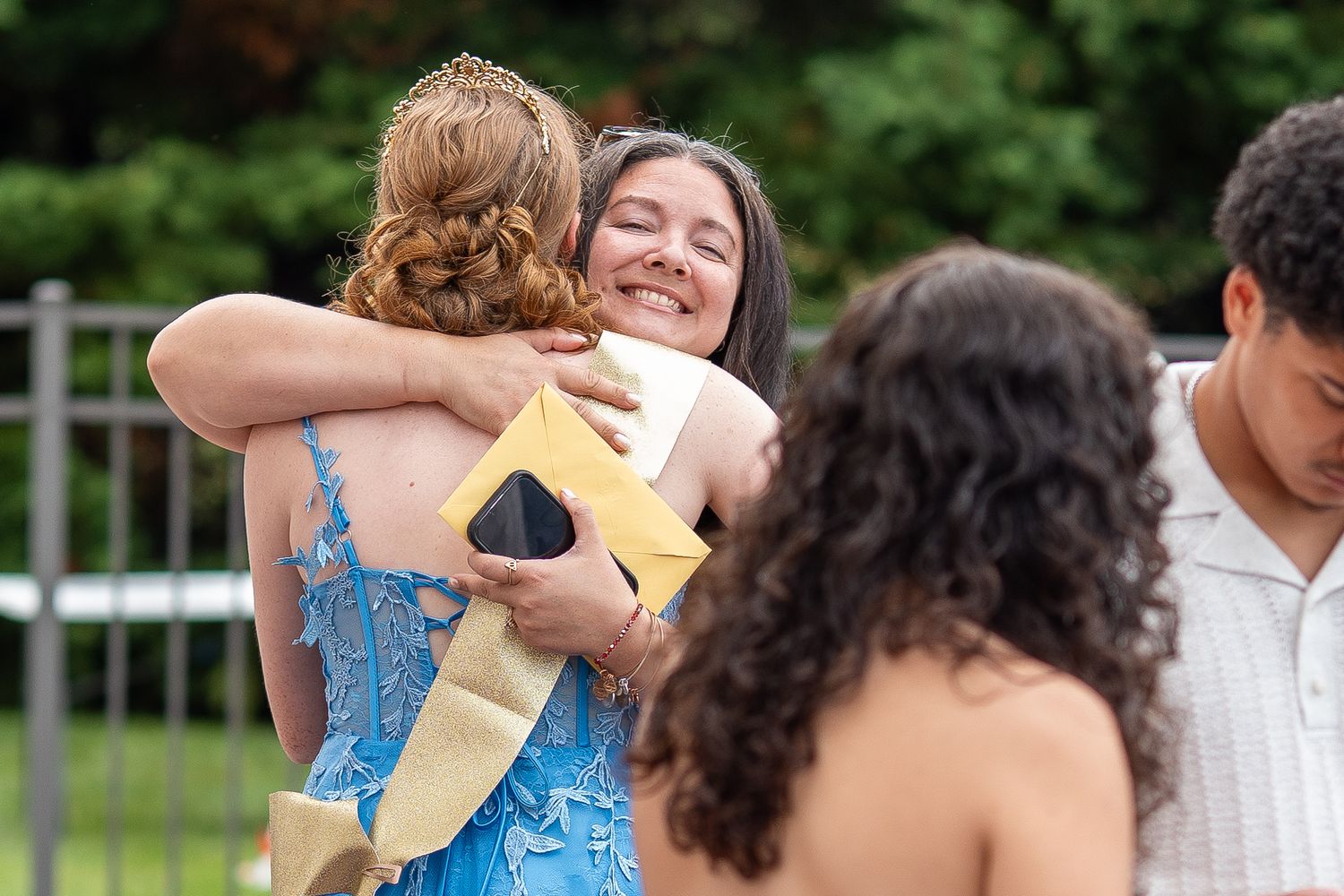 Teen girl in blue formal gown receives warm hug from smiling friend at Sweet Sixteen celebration.
In Forest Hill Maryland