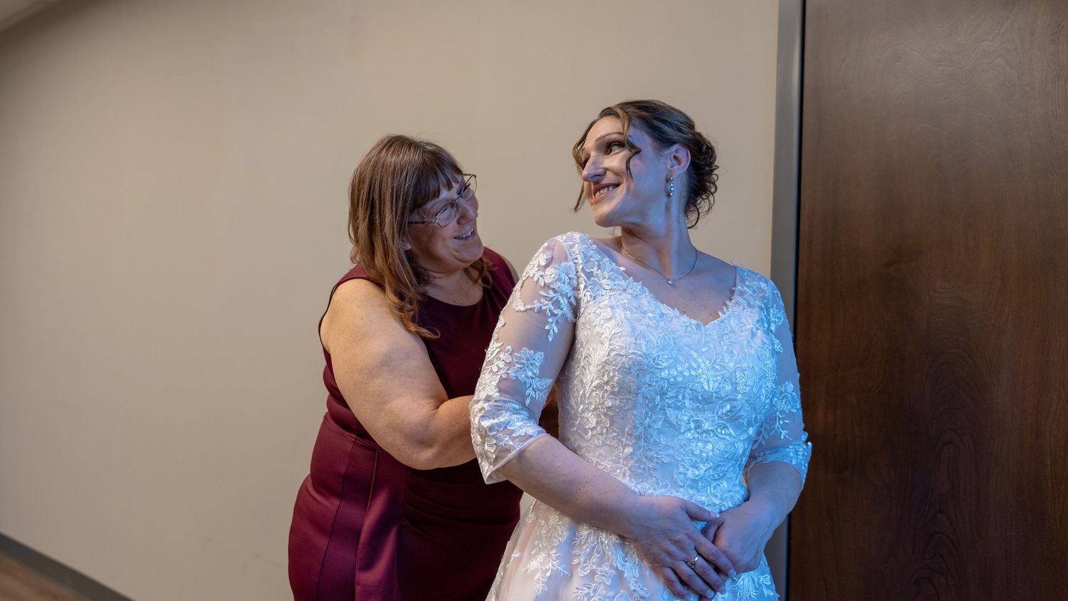 Mother helping bride adjust her lace wedding dress before the ceremony. In Abingdon Maryland