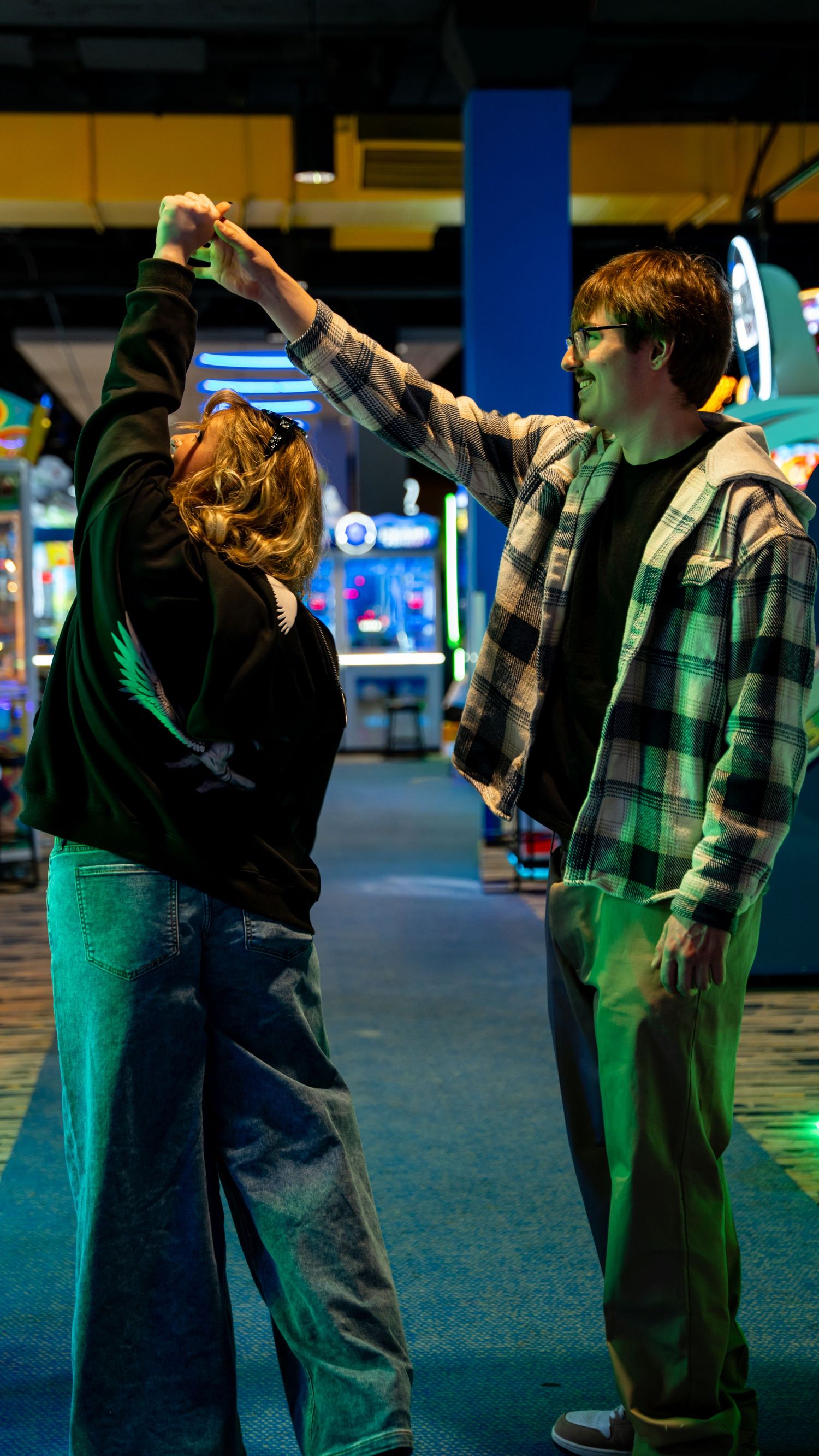 Couple dancing together in a colorful arcade, man spinning woman under his raised arm. In Towson Maryland