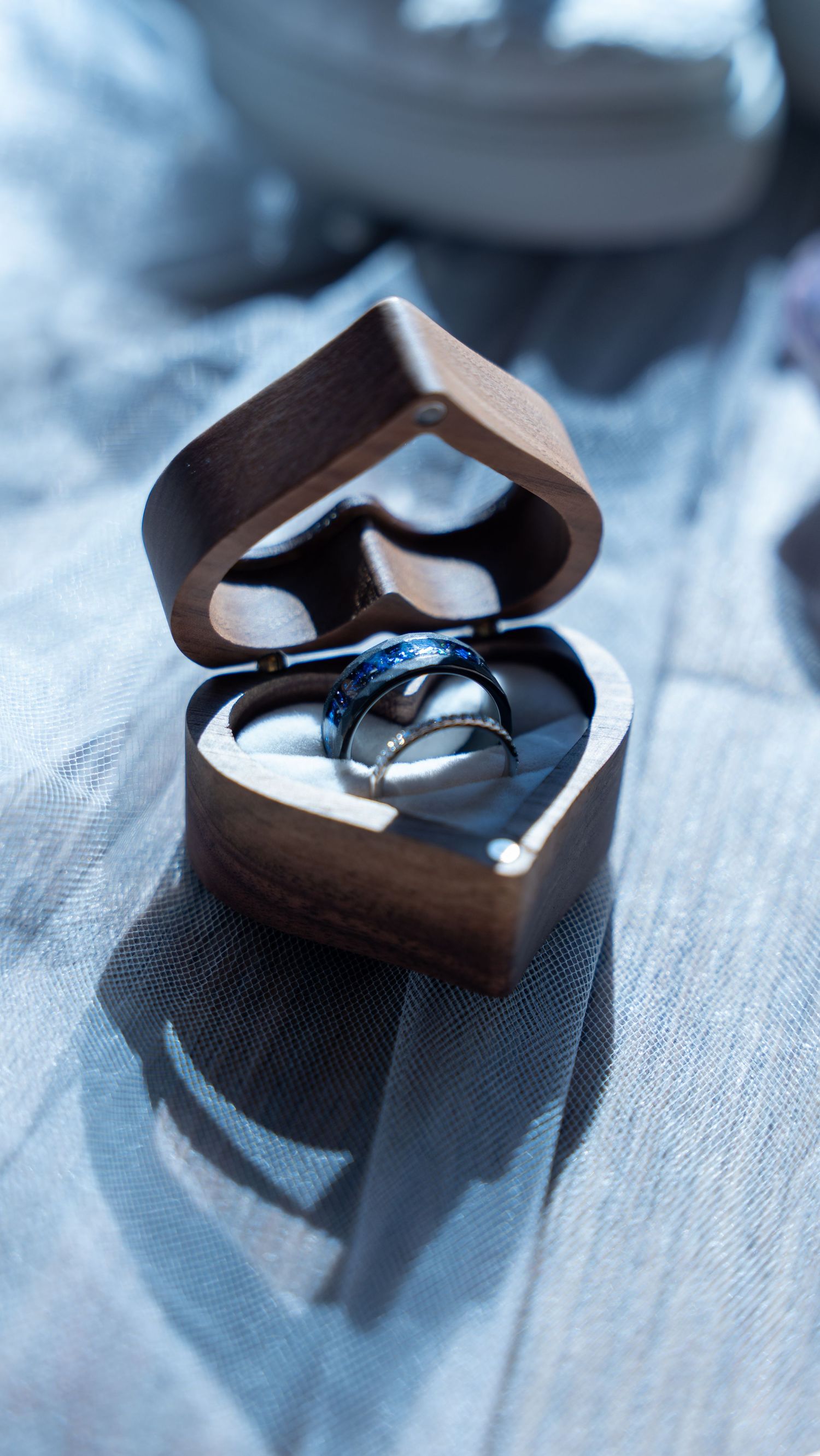 Two wedding bands displayed in a heart-shaped wooden ring box on soft blue fabric.in Abingdon Maryland