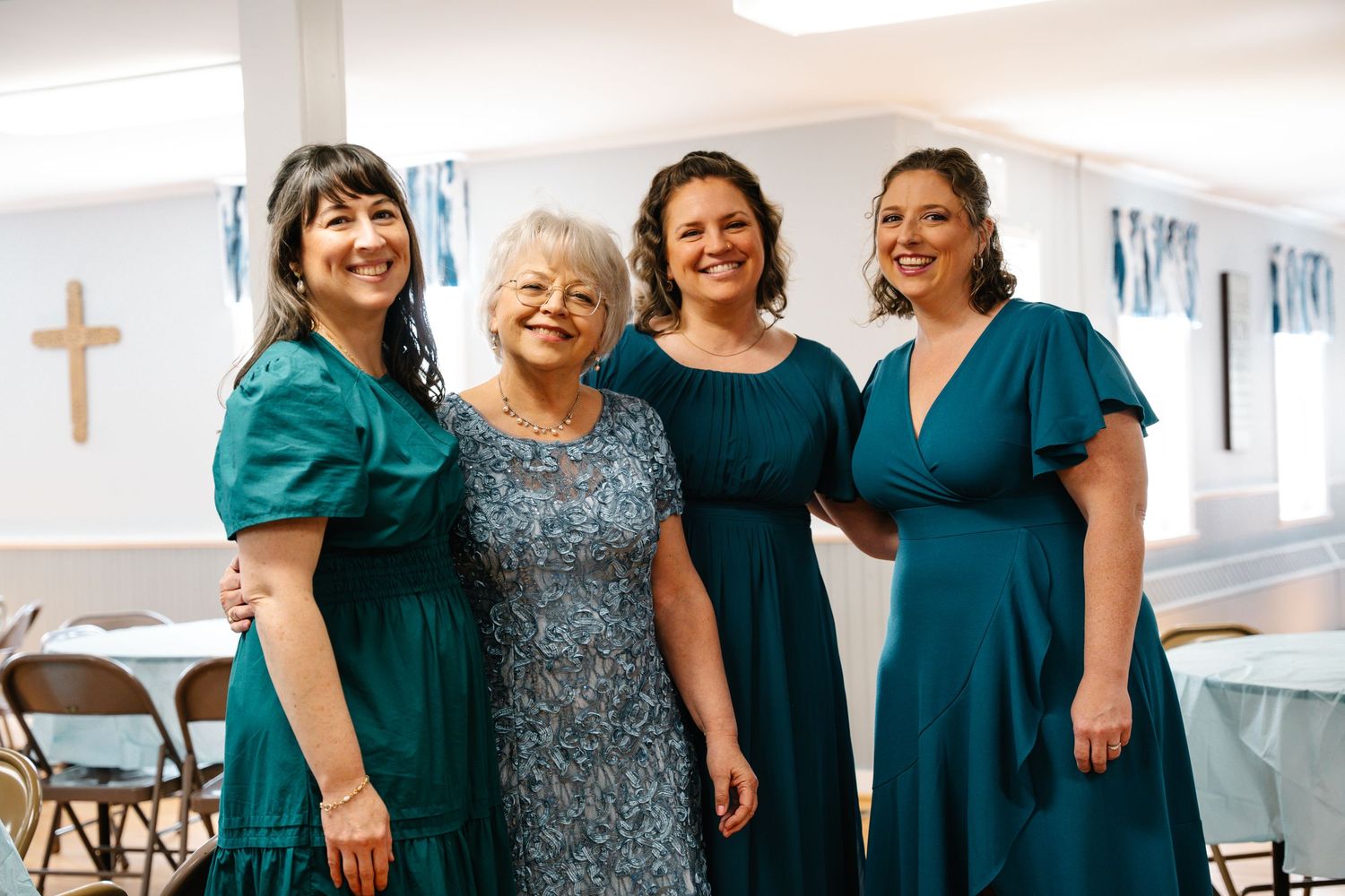 In Bel Air Maryland Four women in teal dresses smile together at a wedding reception inside a church hall.