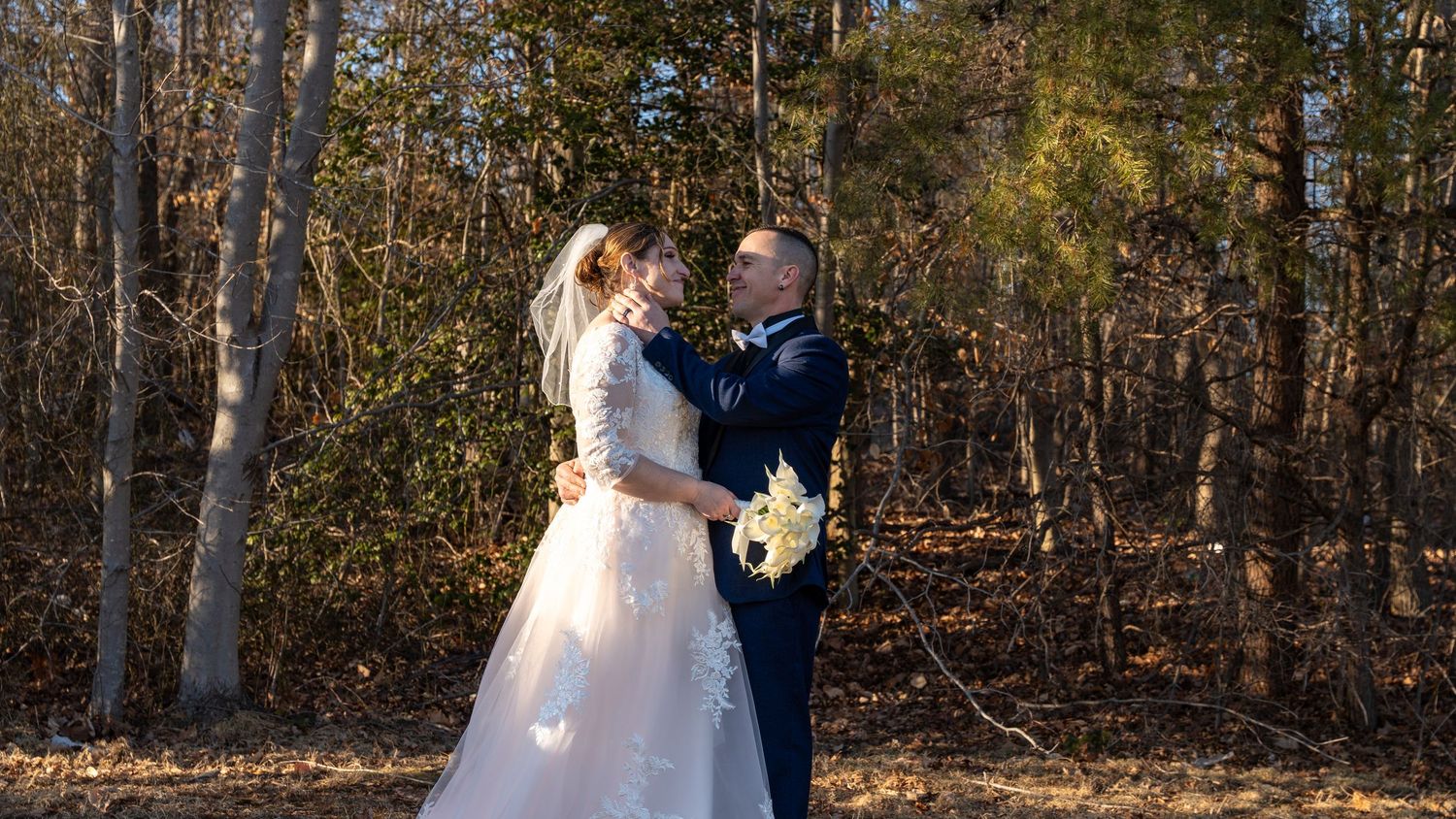 Bride and groom share a romantic moment surrounded by bare autumn trees in an outdoor woodland setting.in Abingdon Maryland