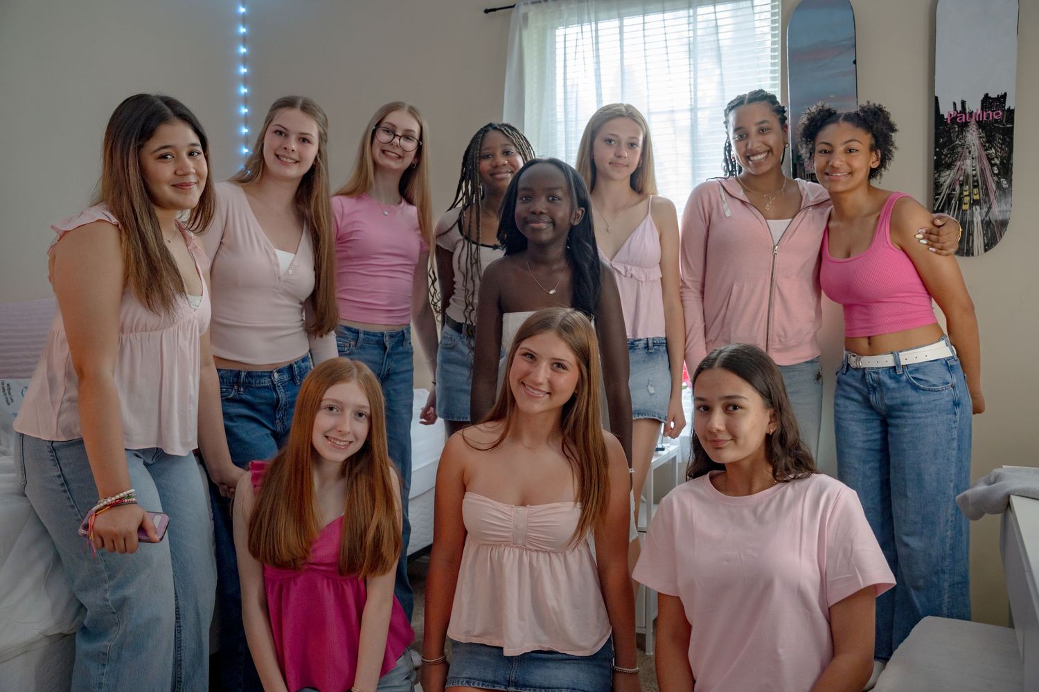 Bel air maryland Group of young women in pink tops and jeans smiling together in a bright bedroom setting.