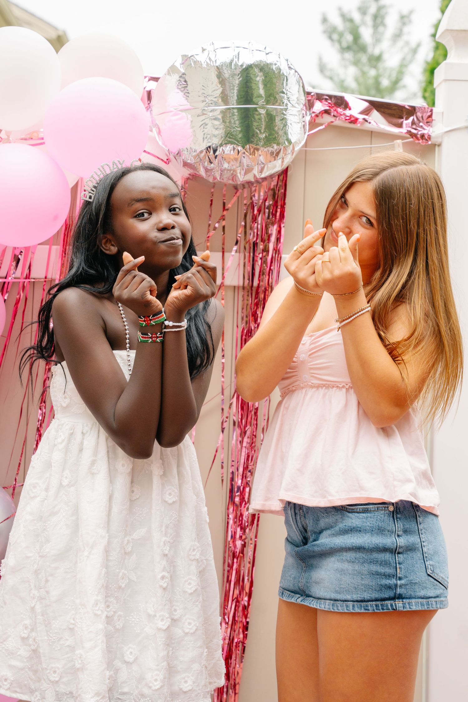 Bel Air MarylandTwo girls posing playfully at a pink balloon birthday party backdrop outdoors.