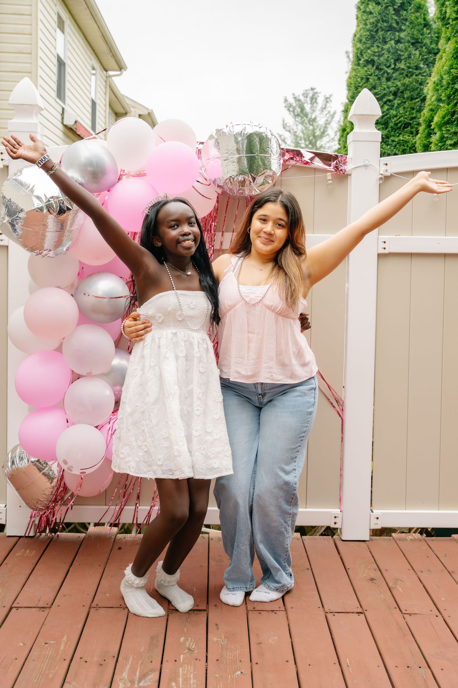 Bel Air Maryland Two girls celebrating with arms raised at a pink and silver balloon party backdrop.