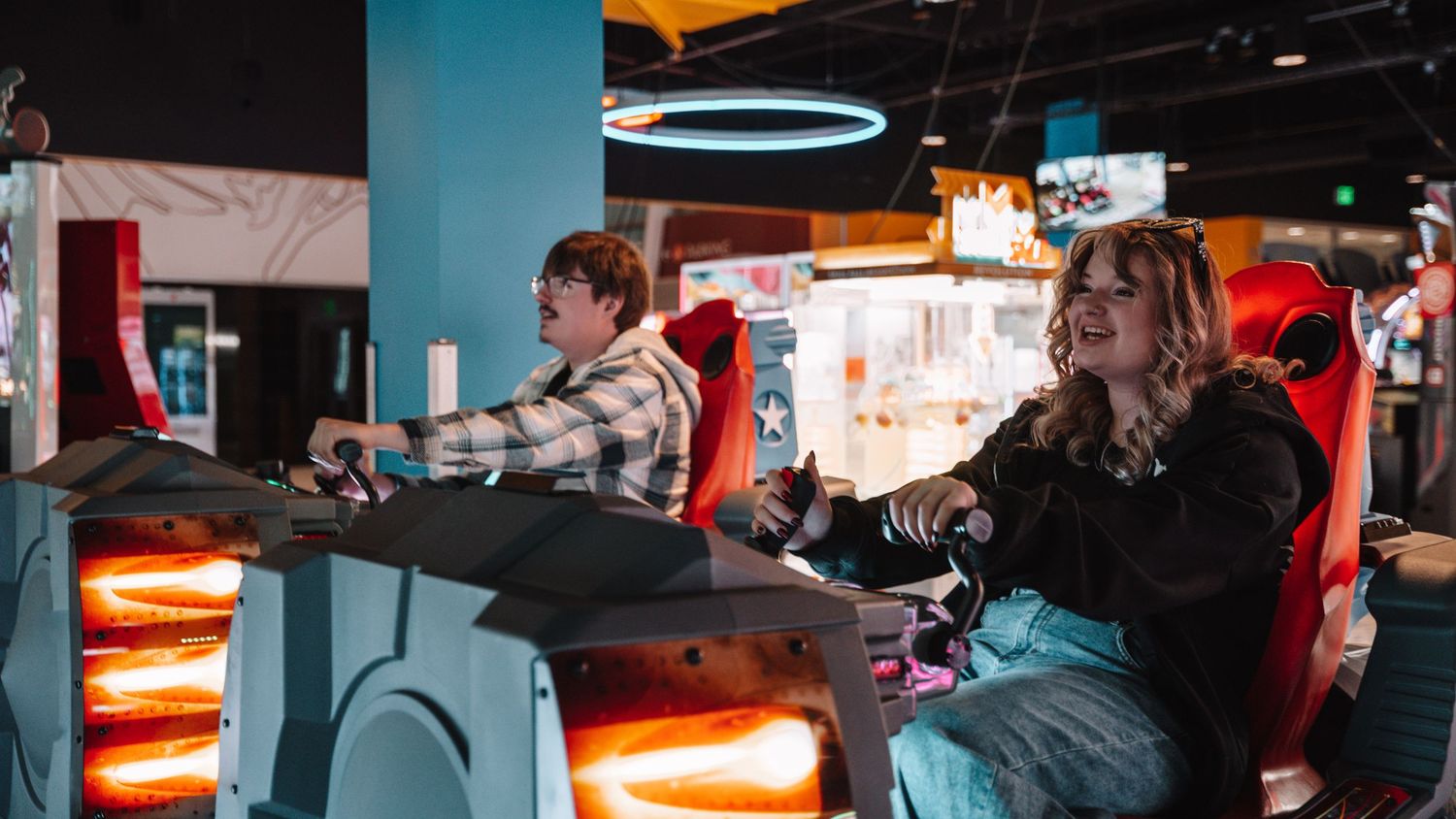 A young couple plays an exciting racing arcade game together at an entertainment venue. In Towson Maryland