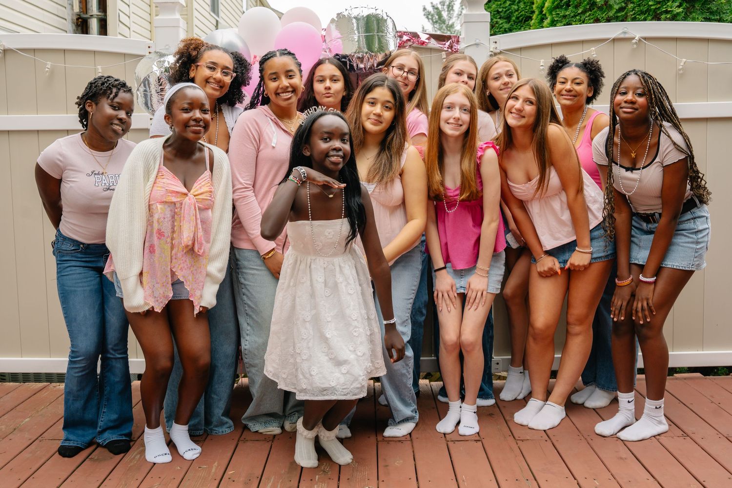 Group of diverse teenage girls posing together at an outdoor birthday party on a wooden deck. bel air maryland